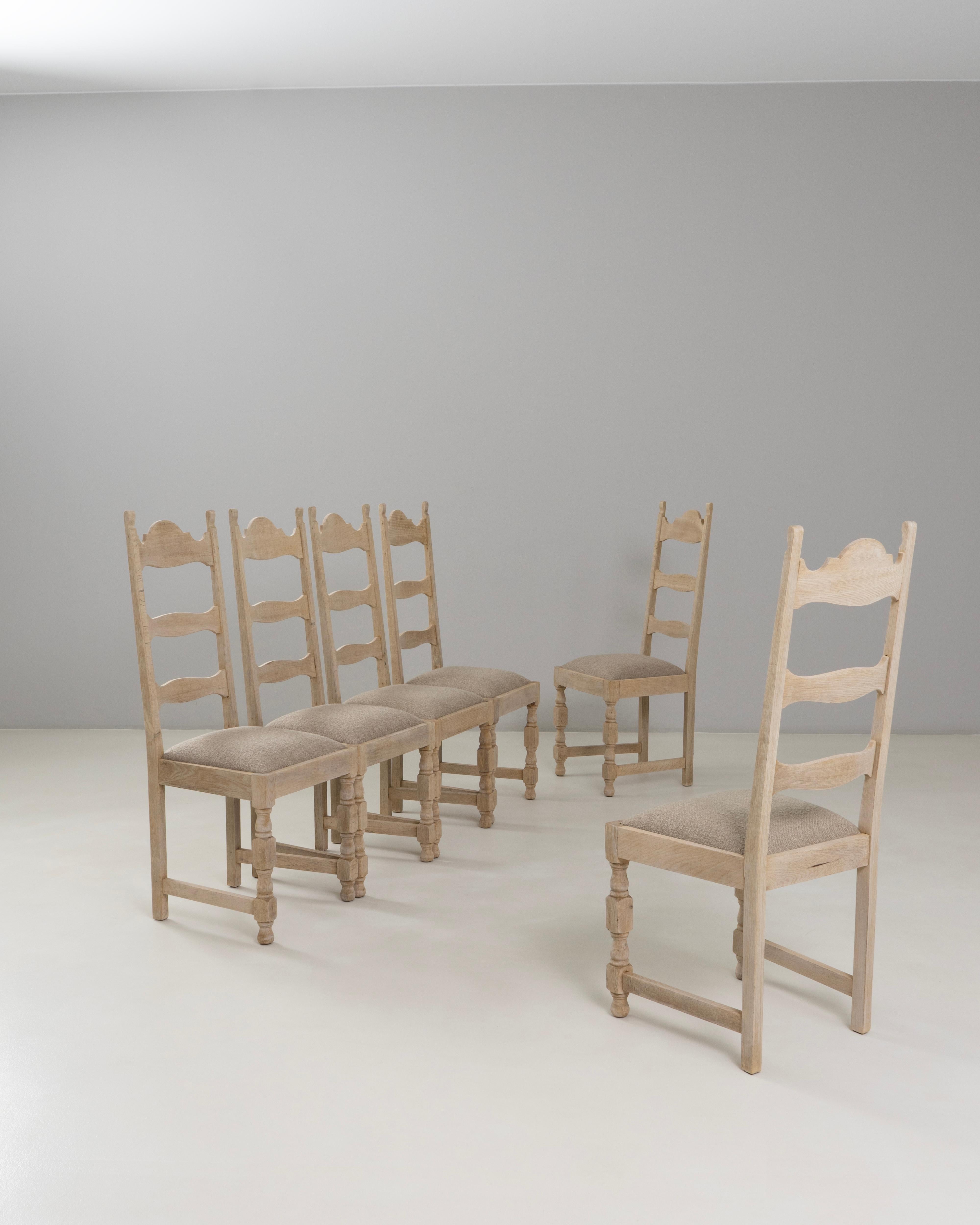 This set of six 1970s Belgian oak dining chairs features a warm, natural finish and a classic ladder-back silhouette that reflects the region’s timeless craftsmanship. Each chair is constructed from solid oak, showcasing subtle variations in grain