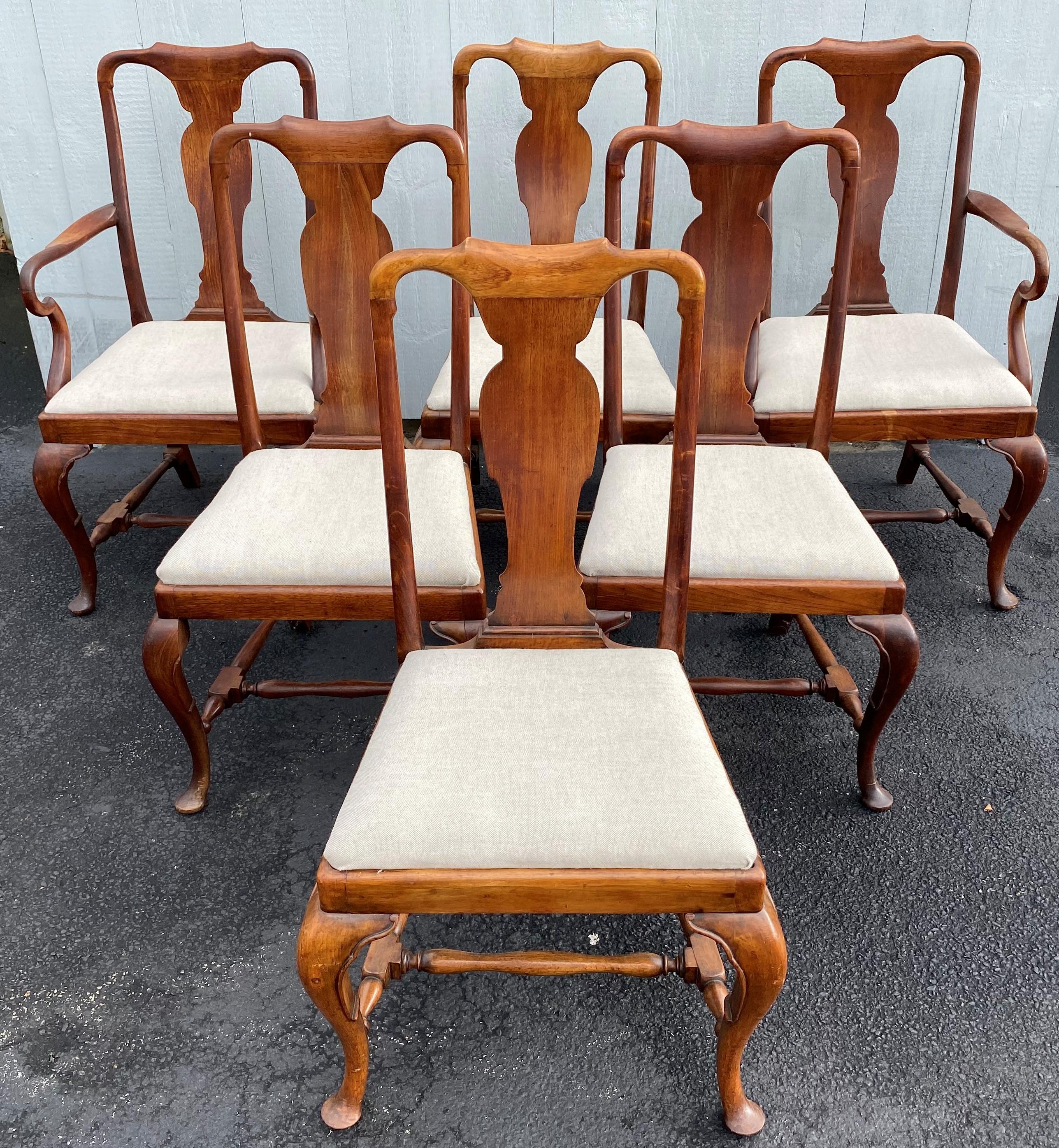 A fine set of six Queen Anne style mahogany dining chairs, including two armchairs and four side chairs, each with spoon backs and cream colored reupholstered slip seats, front carved cabriole legs with pad feet, H form turned stretchers, and