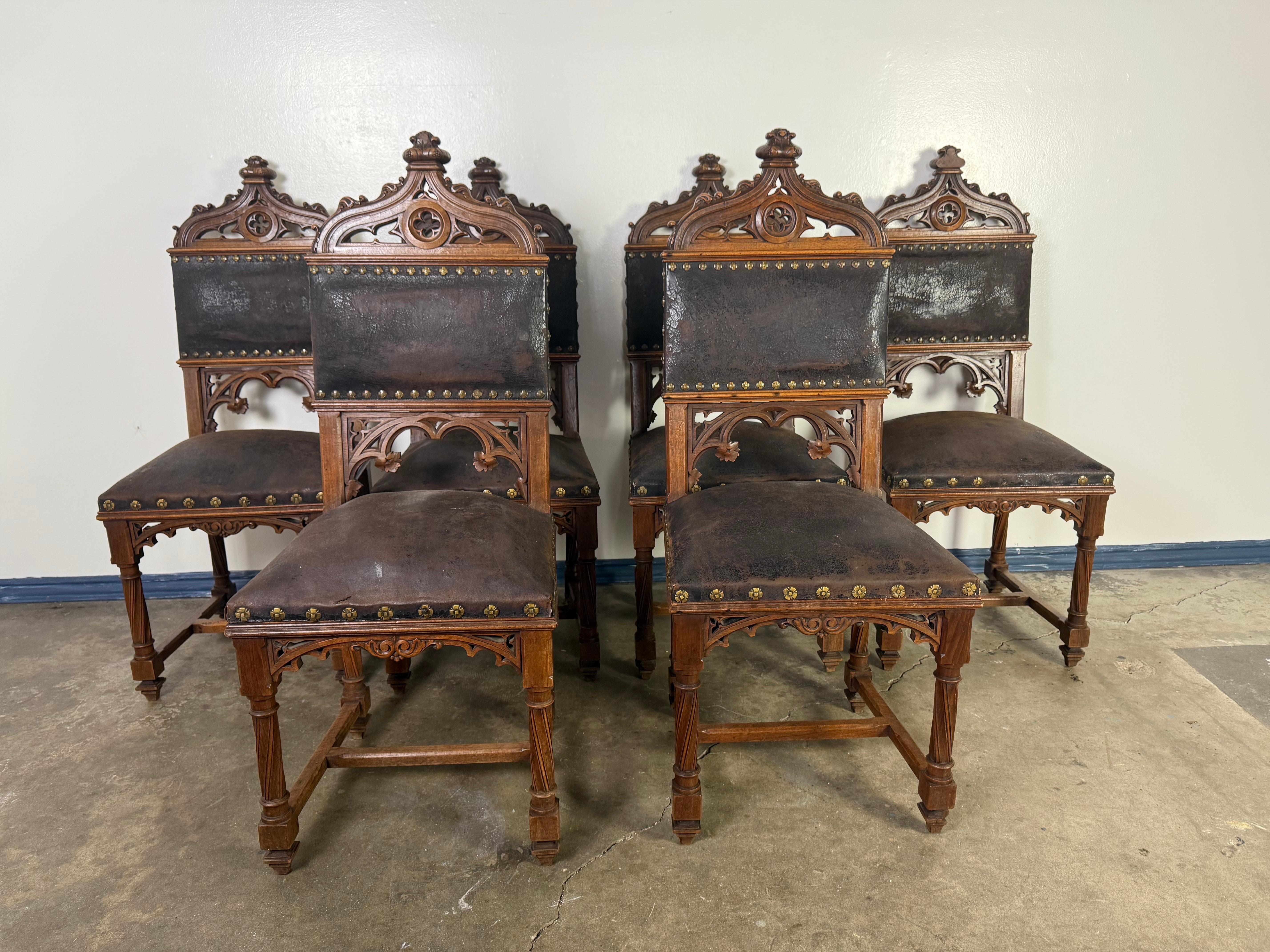 Set di sedie da pranzo in stile gotico italiano del XIX secolo con intricati intagli in legno e rivestimento in pelle scura,  Le cornici sono realizzate in noce con elaborati trafori negli schienali, che ricordano i classici elementi architettonici