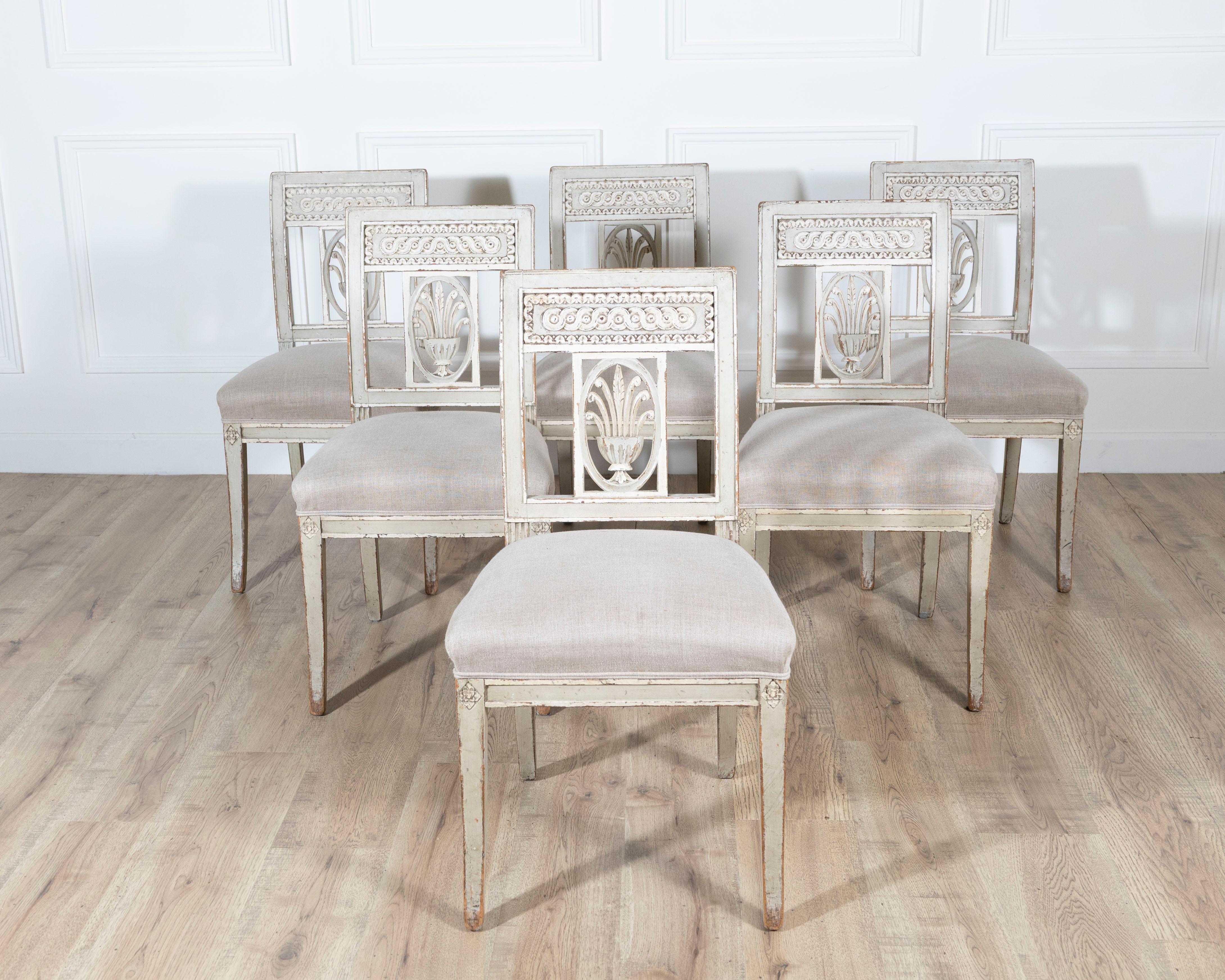A beautiful set of six 19th century Directoire style chairs, each crafted in carved wood and resting on elegant sword legs. The square backs are adorned with finely detailed carving, including a central stylized motif framed by intricate borders,