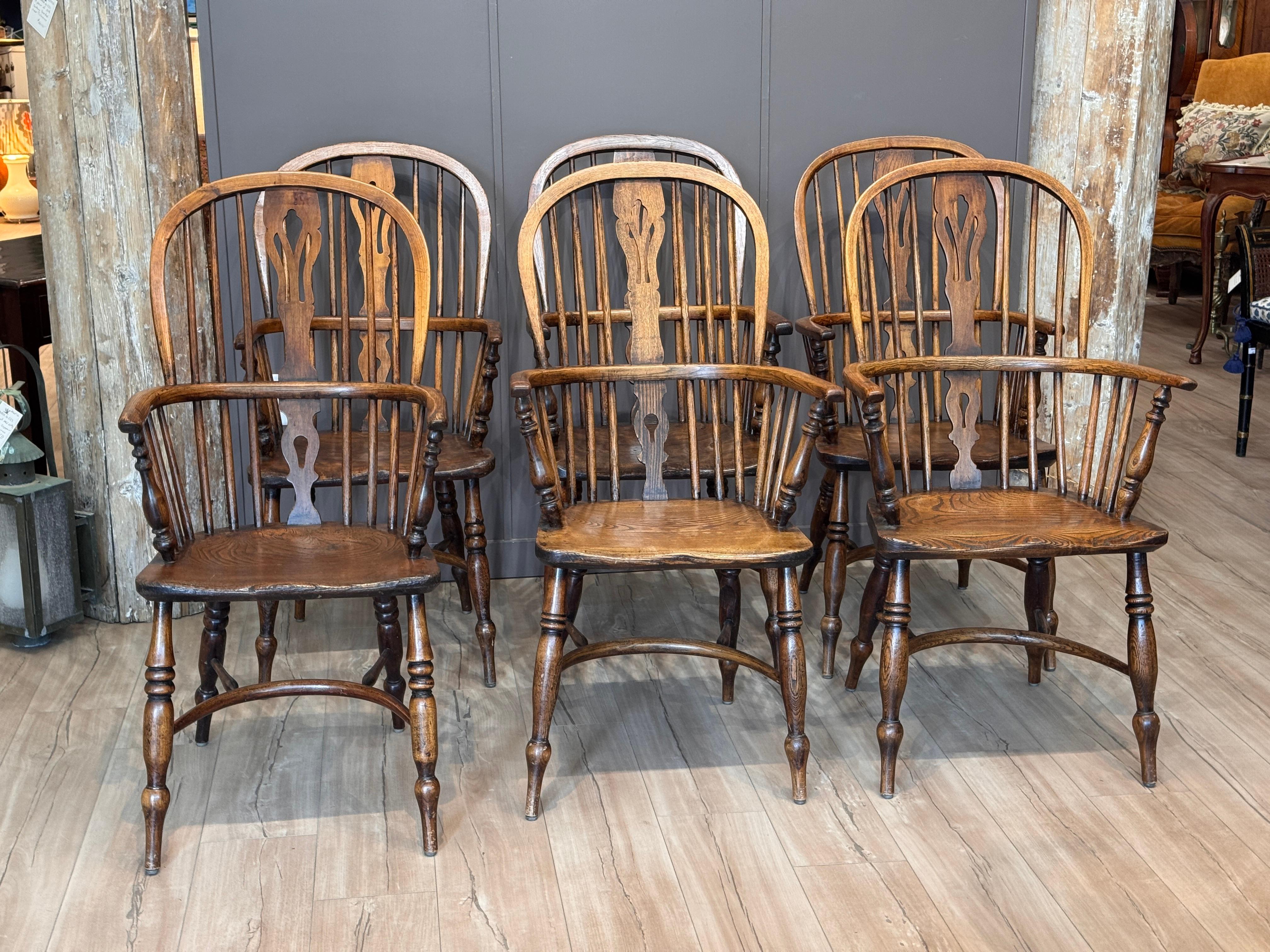 Conjunto de seis sillones Windsor ingleses del siglo XIX, con asientos en forma de silla de montar y tablillas perforadas sobre respaldos de palillo. Cada una con crestas de aro, patas torneadas y bases de camilla. Hermosa variación en la pátina de