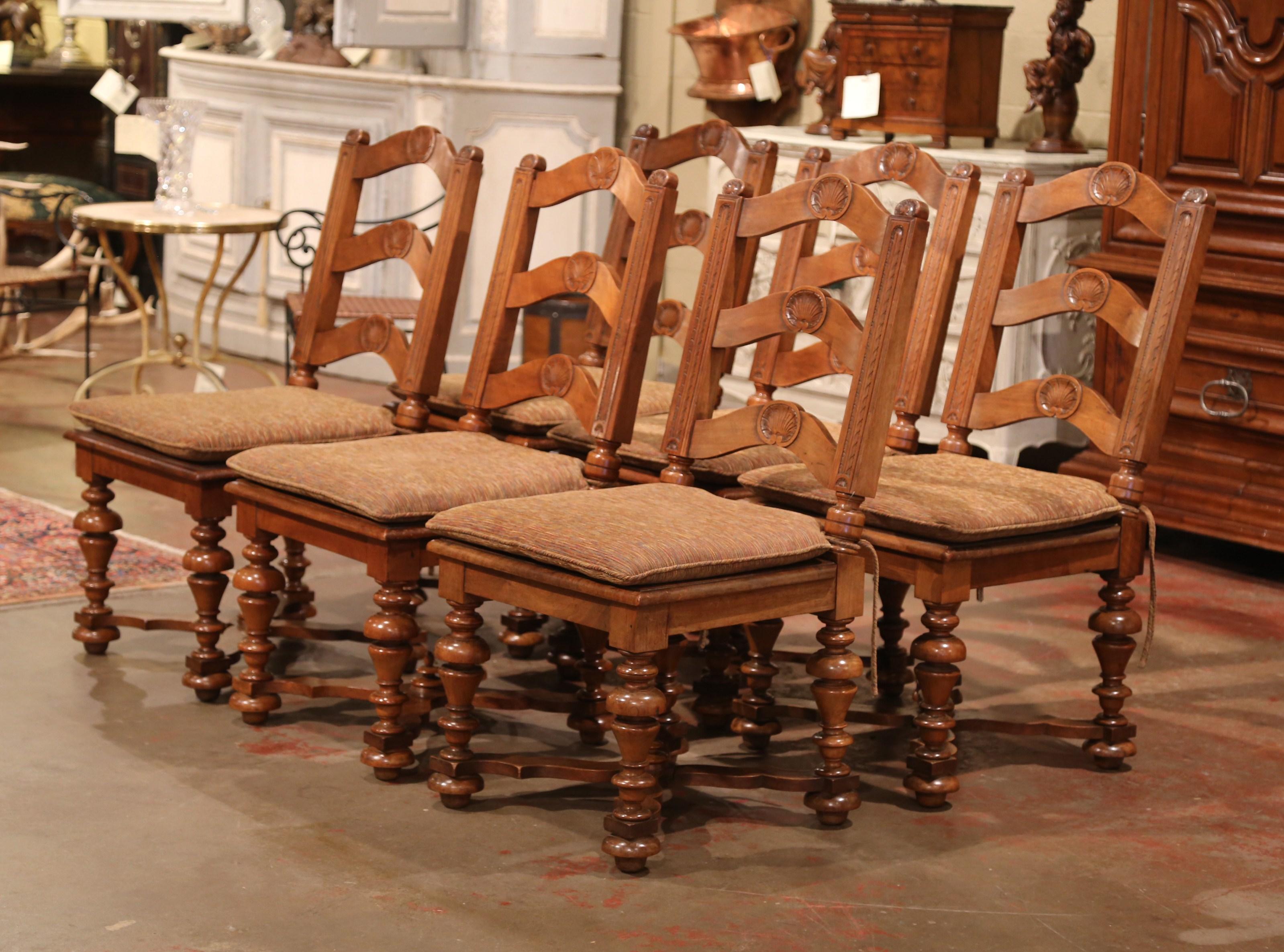 This elegant set of country chairs was crafted in France, circa 1880. Carved from solid walnut, each large chair has a tall pitched back with three ladders embellished by a carved shell motif. The chairs have wide and deep seat over four carved