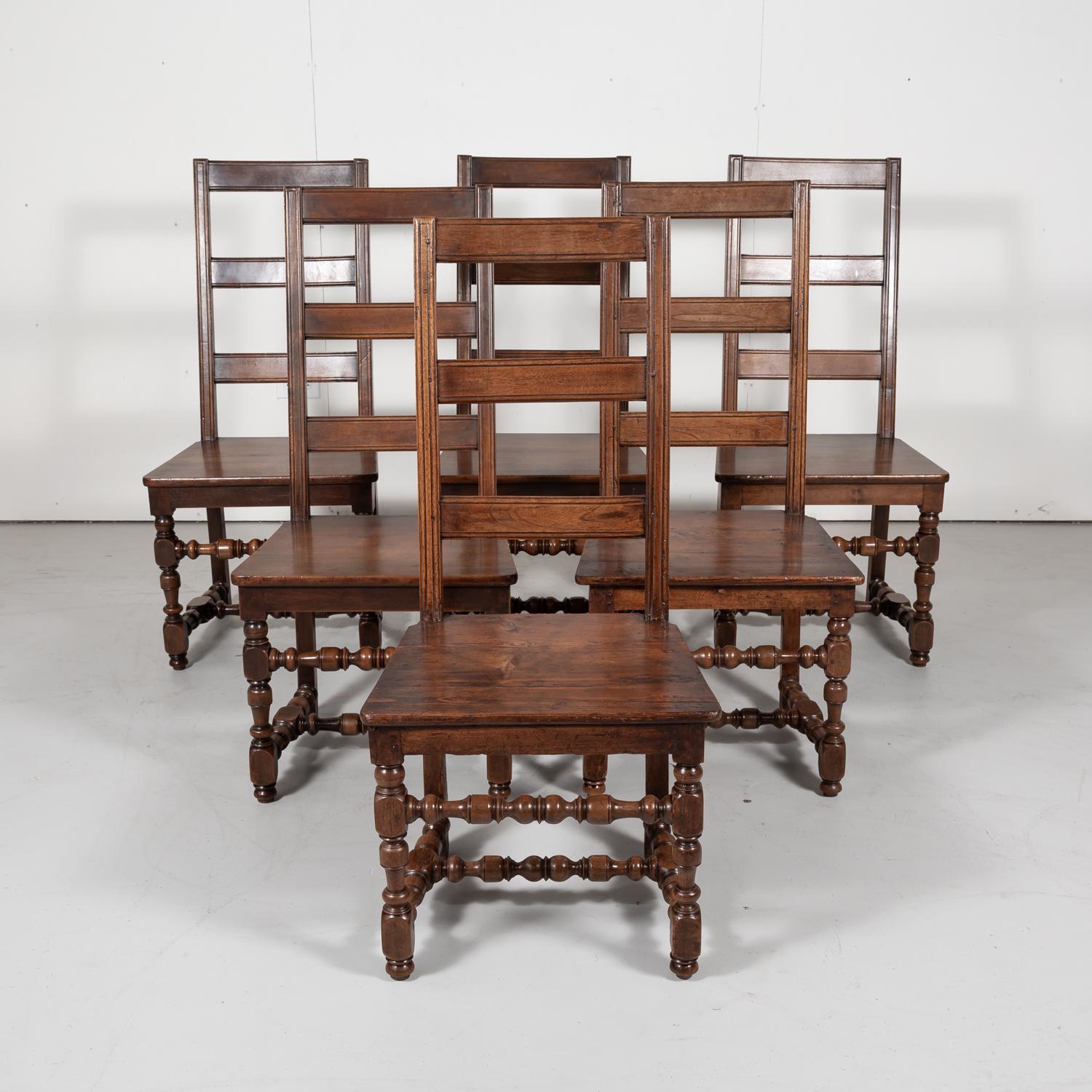 Hard to find set of six French Louis XIV style ladder back dining chairs in walnut, each having a squared back with three horizontal slats and solid wood seat, circa 1890s. Raised on turned front legs and squared back legs with an H-stretcher and