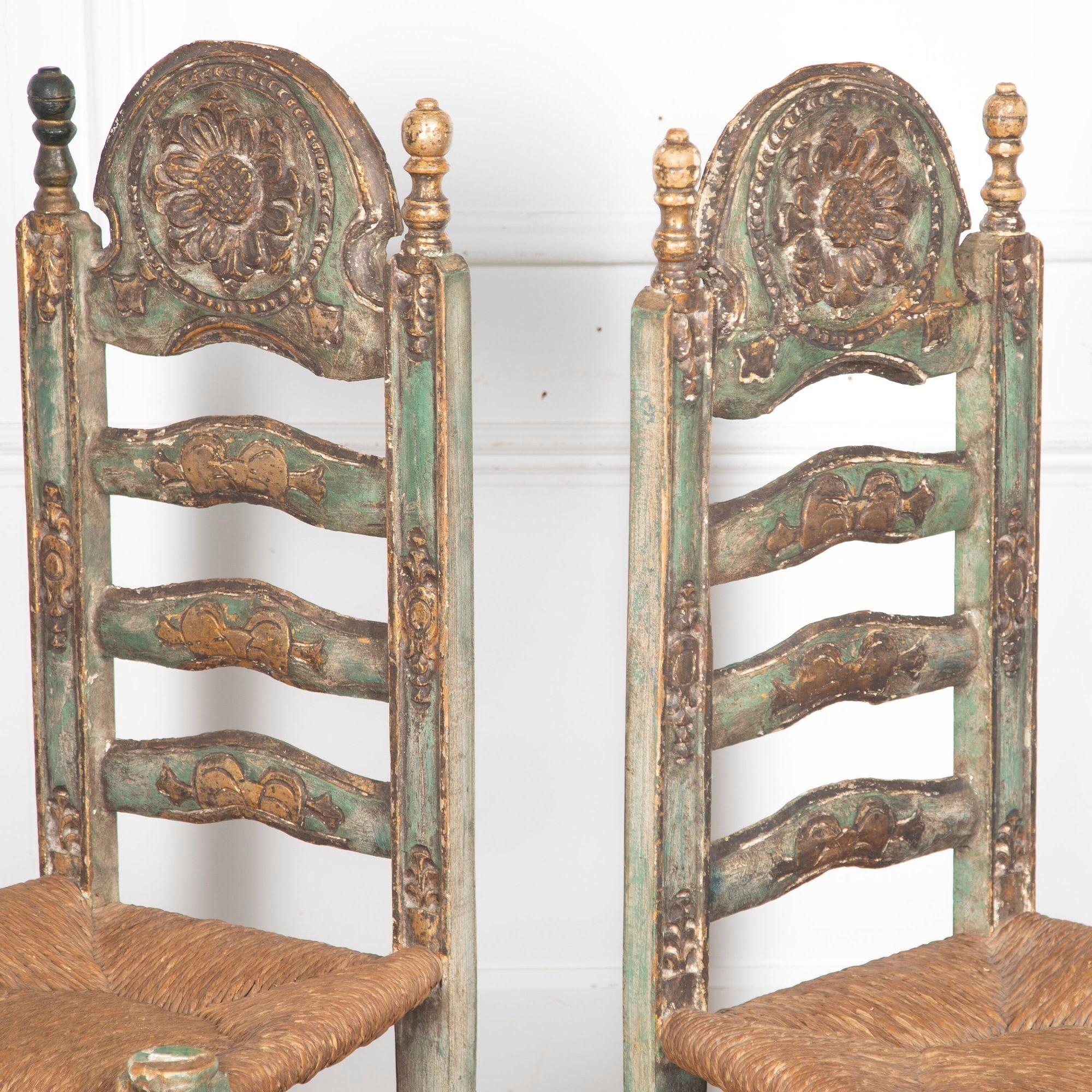 Fabulous set of six early 20th century polychrome high back chairs with strawed seats.
Each features a prominently raised crest on the headrest, beautifully carved with a sunflower. The open ladder back features bow motifs.
The uprights feature