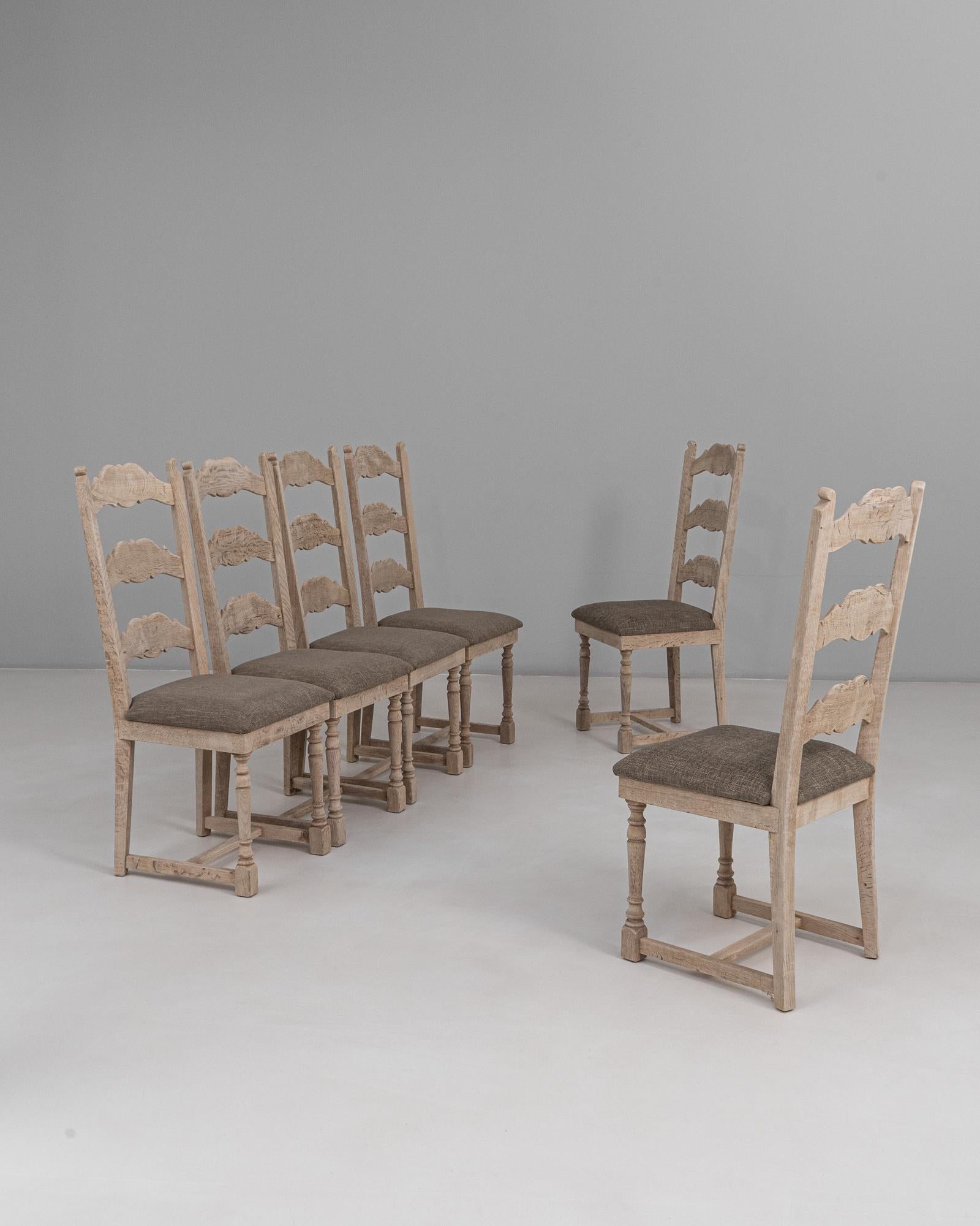 Set di sei sedie da pranzo belghe con schienale a scaletta in Oak del XX secolo. Queste affascinanti sedie belghe hanno una struttura in rovere massiccio con una finitura chiara e delicatamente invecchiata che mette in risalto la texture naturale