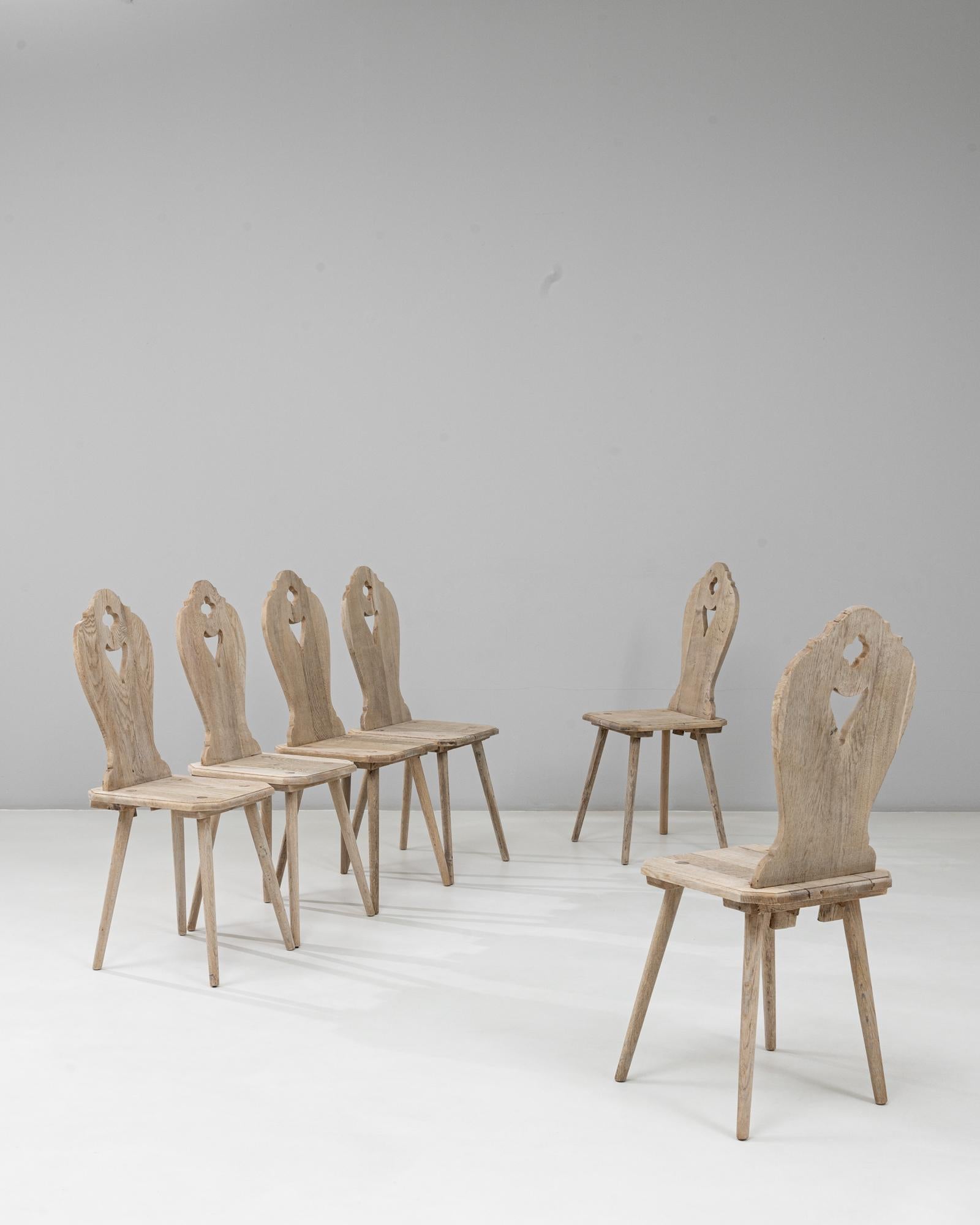 Cet ensemble de six chaises de salle à manger alpines en chêne français du XXe siècle présente le charme de l'artisanat montagnard traditionnel avec leurs dossiers sculptés, leurs découpes en forme de cœur et leur patine usée par le temps. Chaque