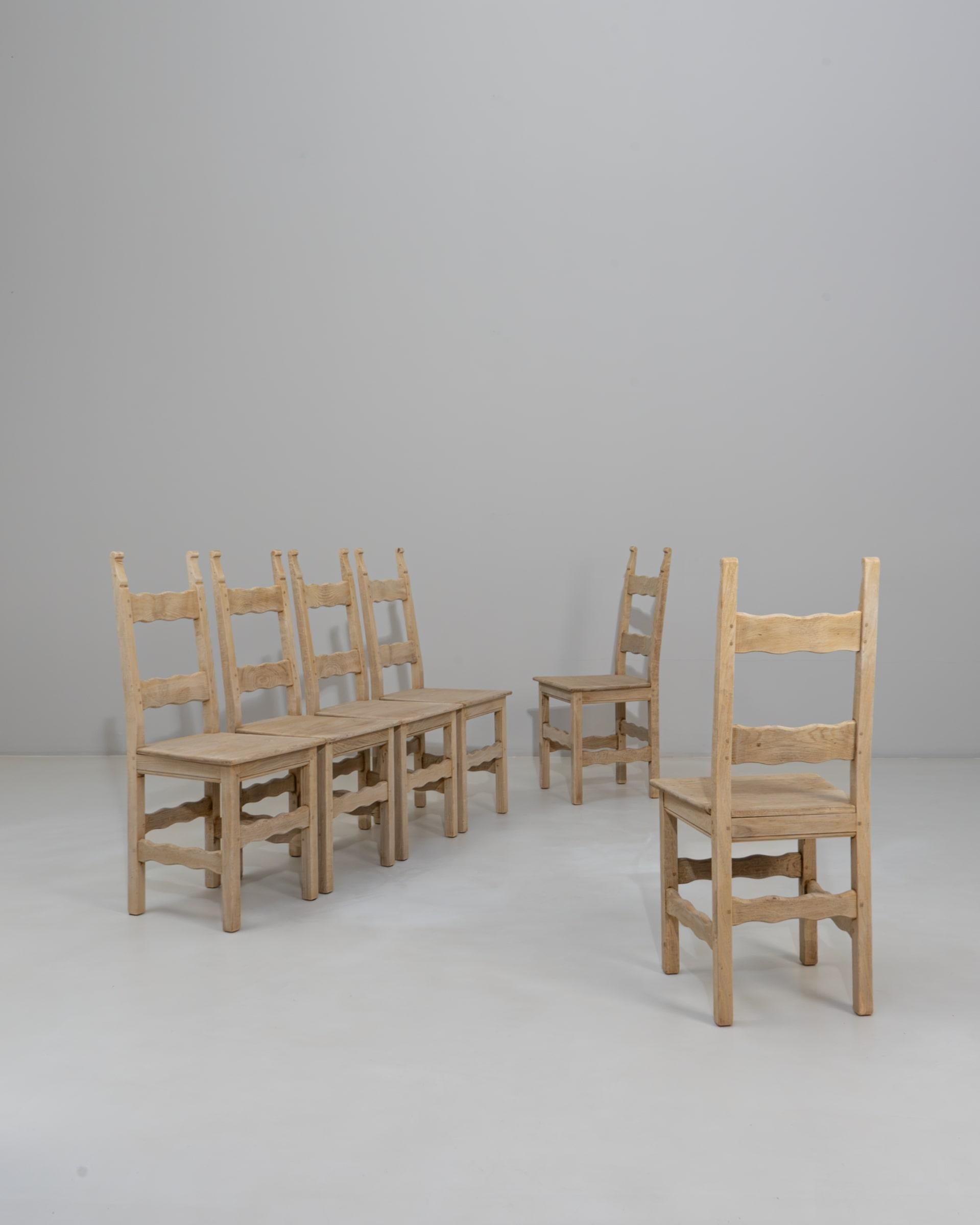 Set di sei sedie da pranzo con schienale a scaletta in Oak del XX secolo. Realizzato in rovere massiccio, questo incantevole set presenta le classiche Silhouette con schienale a scaletta, doghe delicatamente sagomate e robuste gambe quadrate
