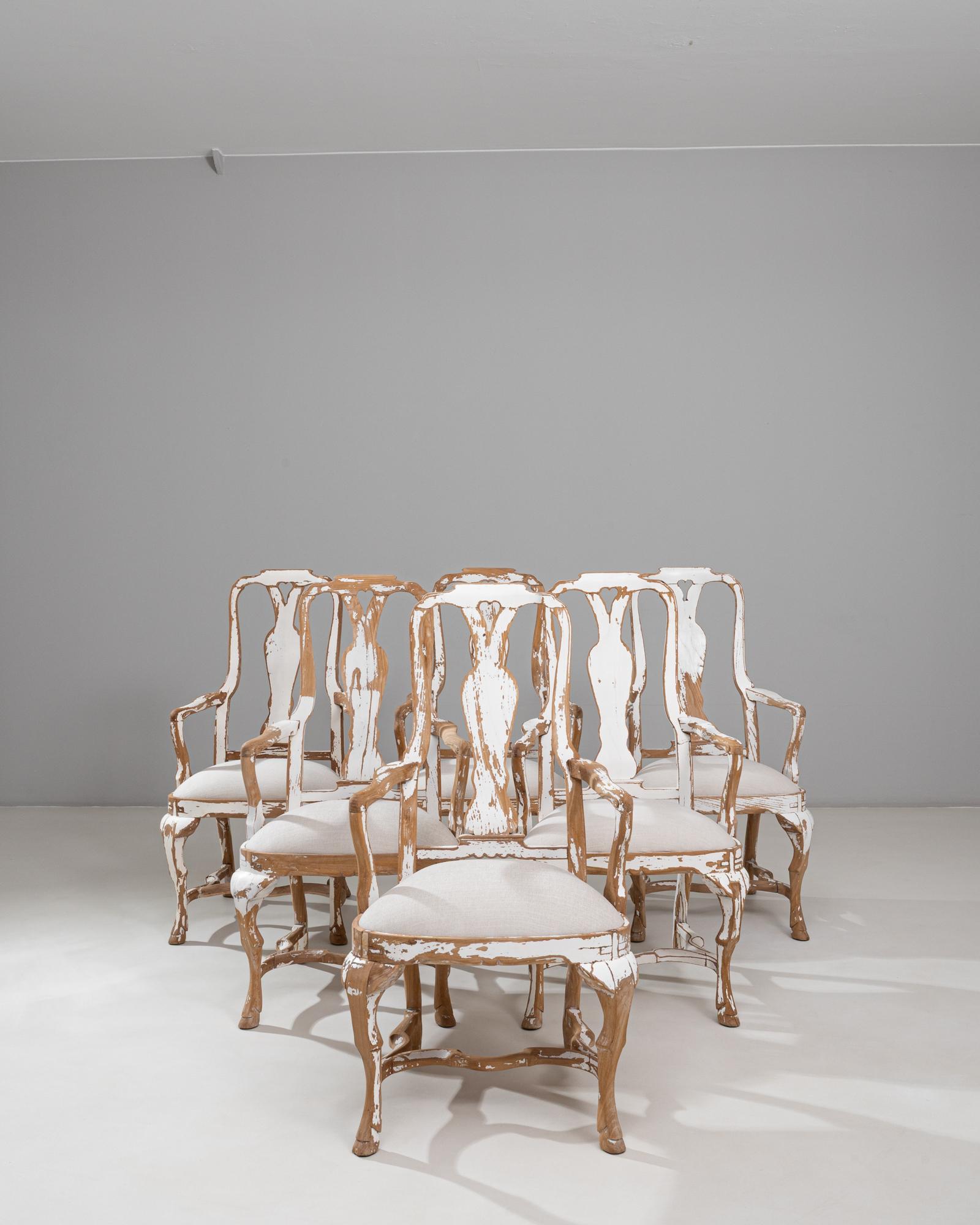 Este juego de seis sillas de comedor suecas del Renacimiento Rococó del siglo XX presenta elegantes siluetas y un bello acabado patinado en madera envejecida que resalta su forma escultural. Cada silla muestra las características líneas