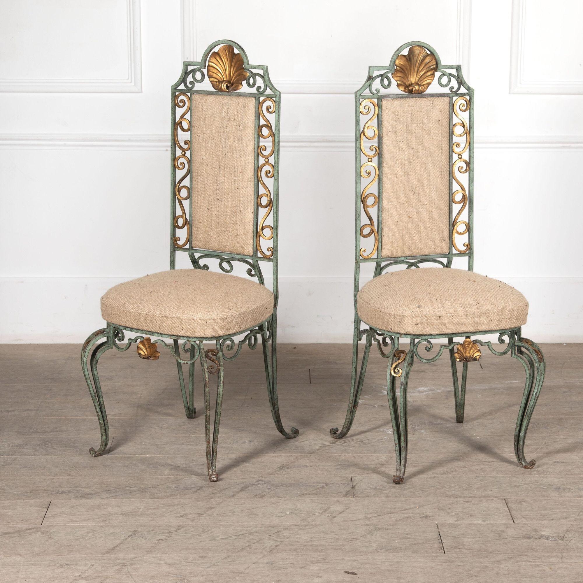 Set of six elegant and regal 1940s wrought iron dining chairs with twisted and curlicue detailing.
The frames are hammered iron with elaborate scrollwork in verdigris and gold finish. The top crests have large shell shaped mouldings in gold