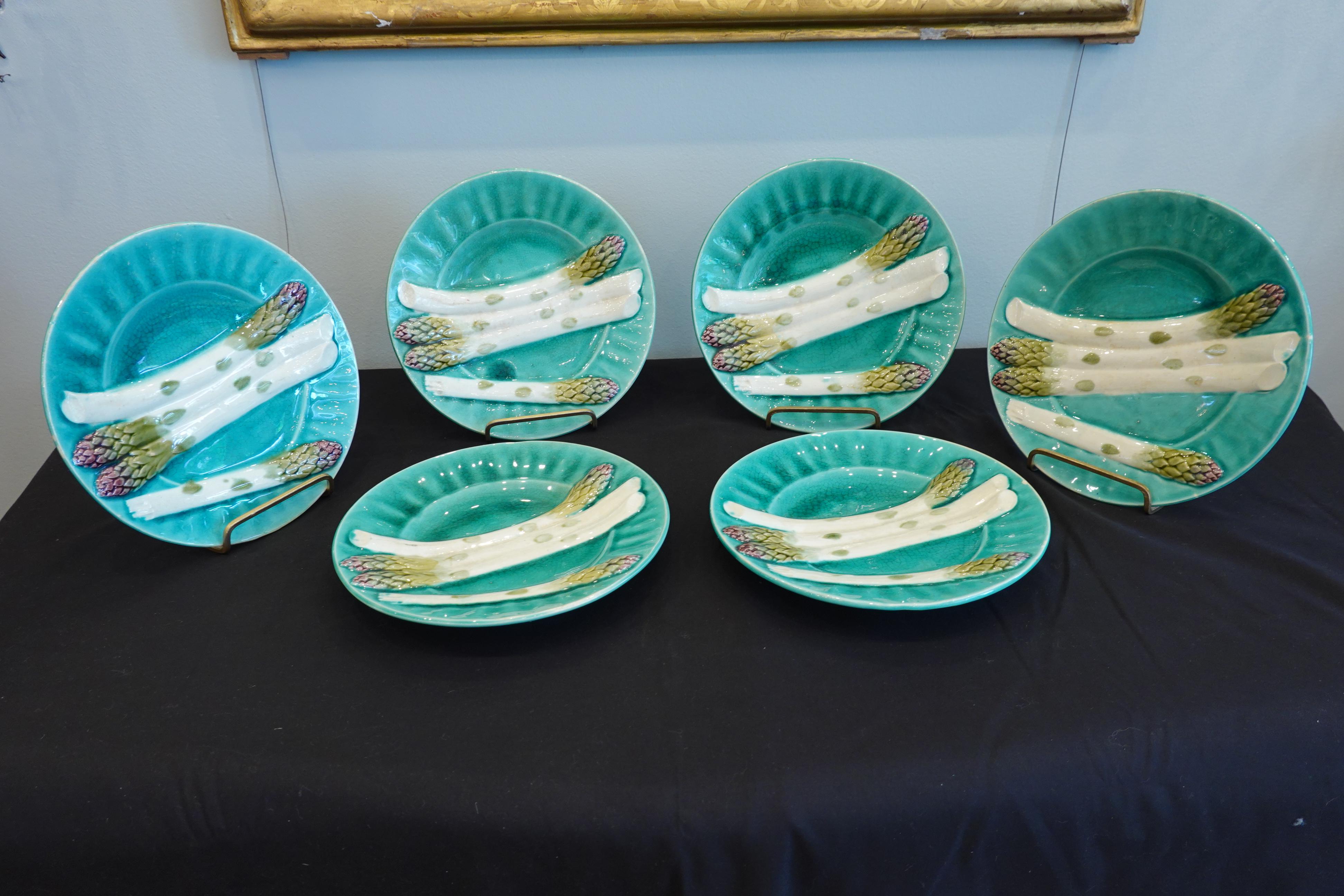Set of very decorative, late 19th century blue-green French Majolica asparagus plates, hand-painted in white, green and purple, showing four asparagus spears in relief, and with fluted rims. The underside is stamped 