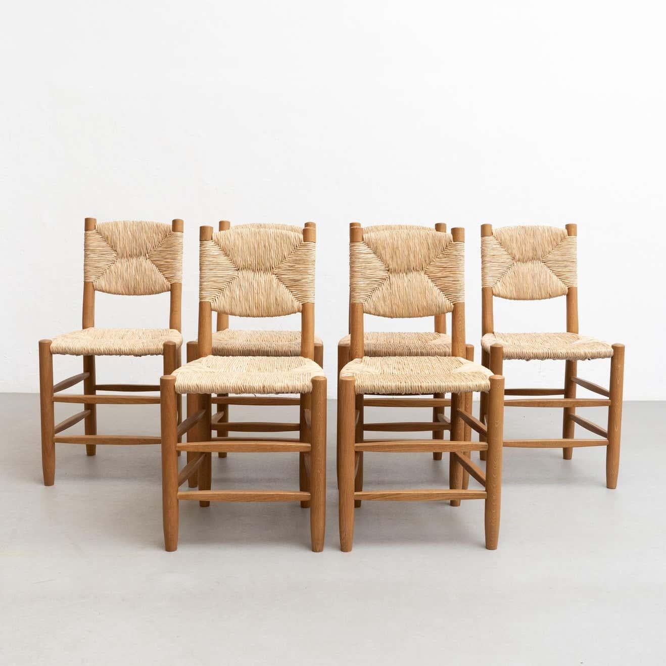 Set of 8 chairs designed in the style of Charlotte Perriand. 

Made by unknown manufacturer in France, circa 1980.

In good original condition, with minor wear consistent with age and use, preserving a beautiful patina.

Materials:
wood and