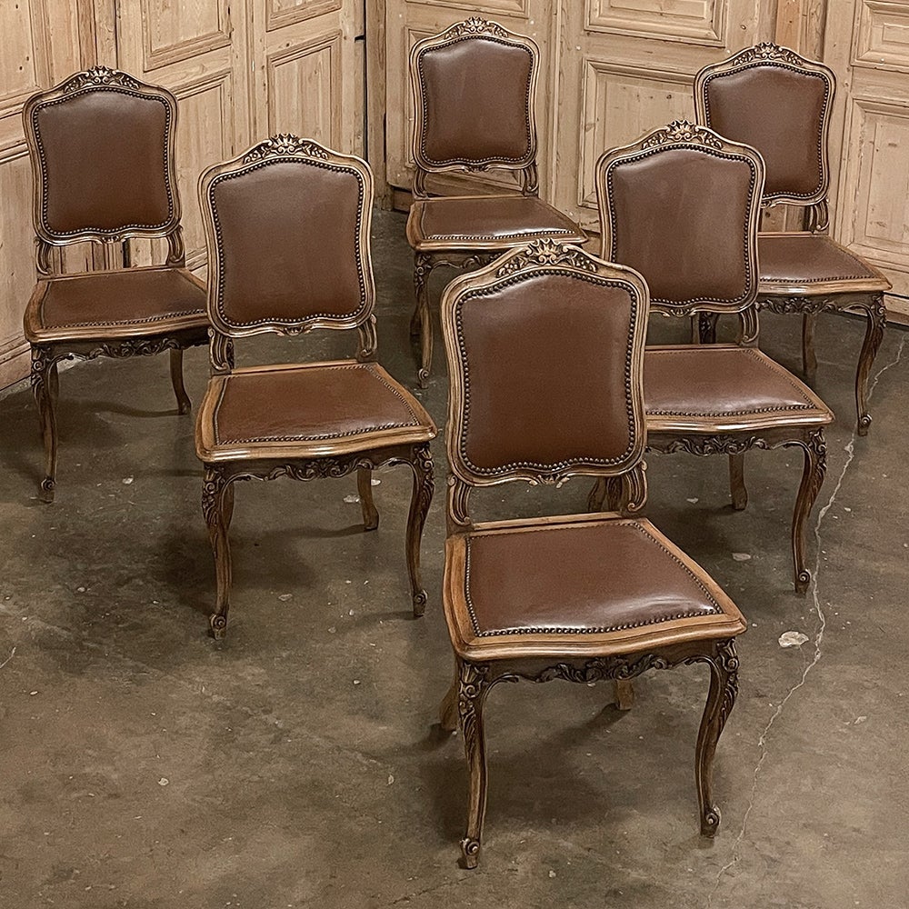 Set of six antique French Louis XIV walnut dining chairs reflect an elegant sophistication that is truly timeless! Gracefully contoured frames include a double arched seatback crown centered with a sculpted shell that is flanked by floral sprays.
