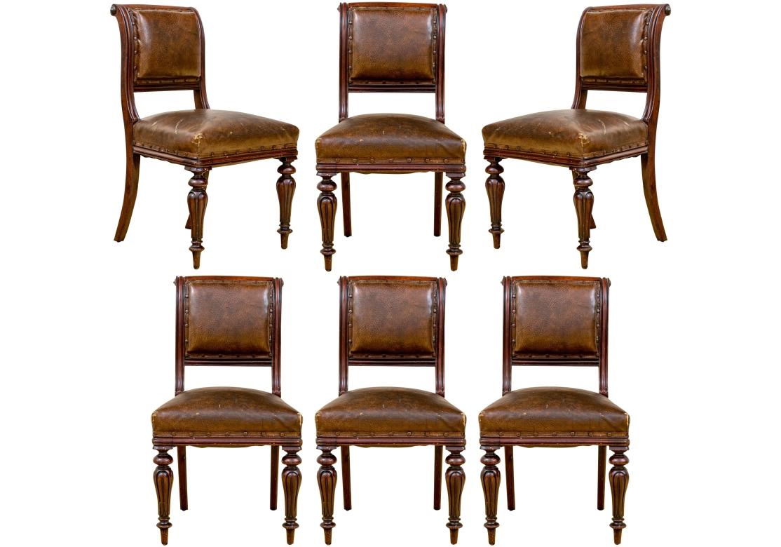 A Rustic set of  Six mahogany frame chairs having strong traditional form with shaped and carved legs, upswept backs, color coordinated nail-head trim and notable distressed leather upholstery. The Set has good weight and are comfortable.