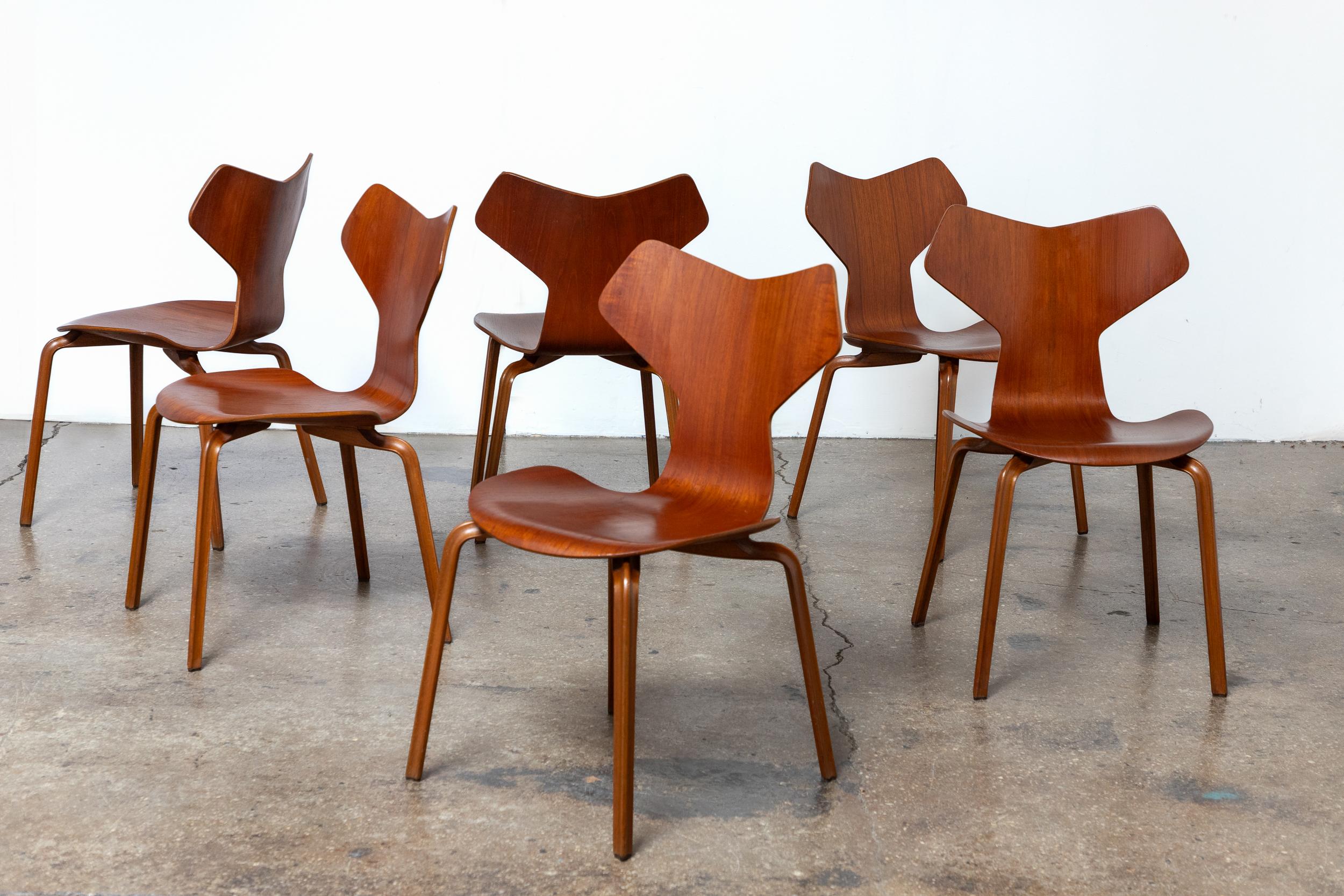 Set di sei sedie da pranzo modello 4130 Grand Prix, disegnate da Arne Jacobsen per Fritz Hansen e vendute al dettaglio da Illums Bolighus. Il guscio scolpito ha una silhouette nitida e grafica, mentre il teak scelto dona calore e variazione delle