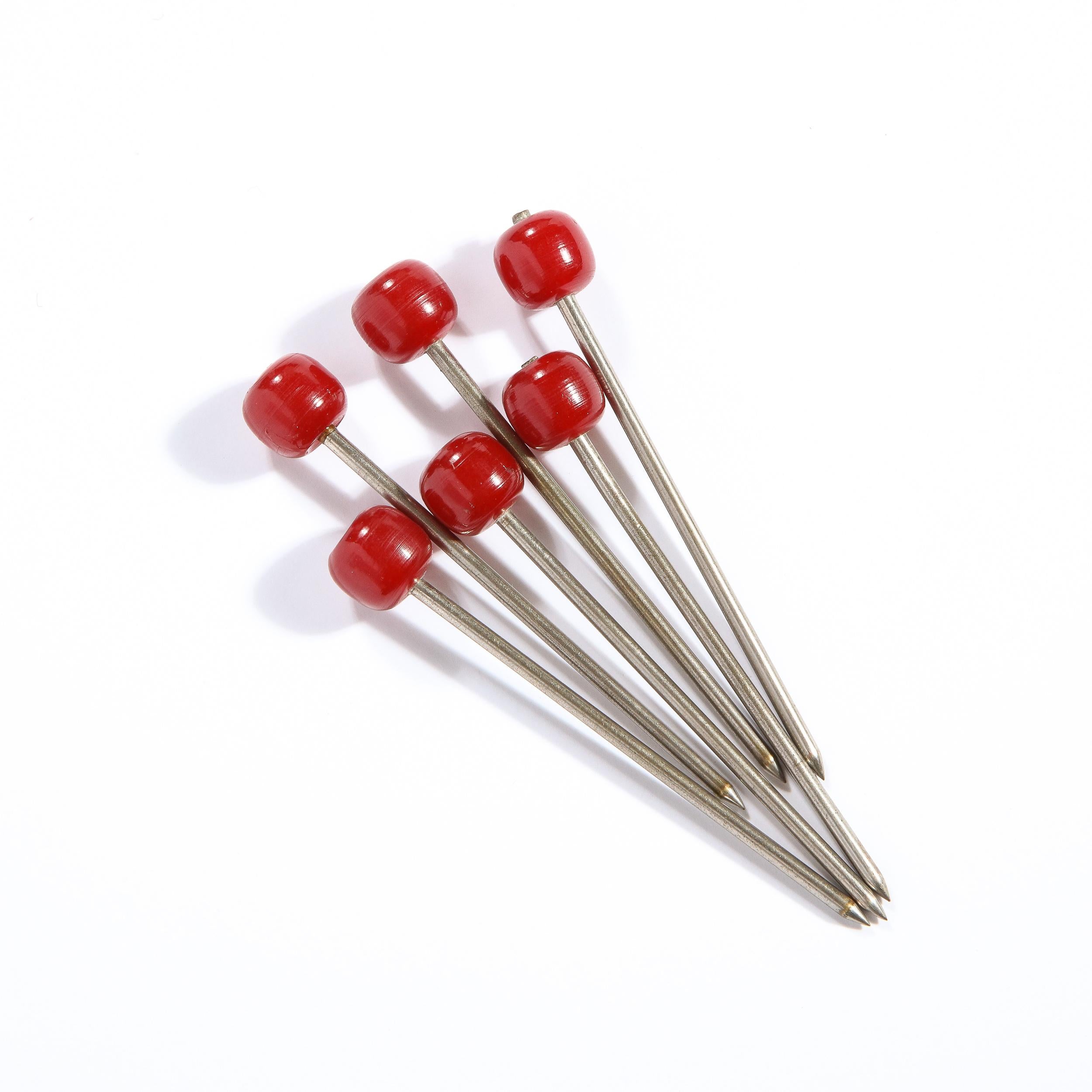 This refined set of six cocktail picks were realized in the United States, circa 1930. It features an orbital end in carnelian bakelite that attaches to a cylindrical stainless steel rod with a pointed end- ideal for spearing olives (or pearl onions
