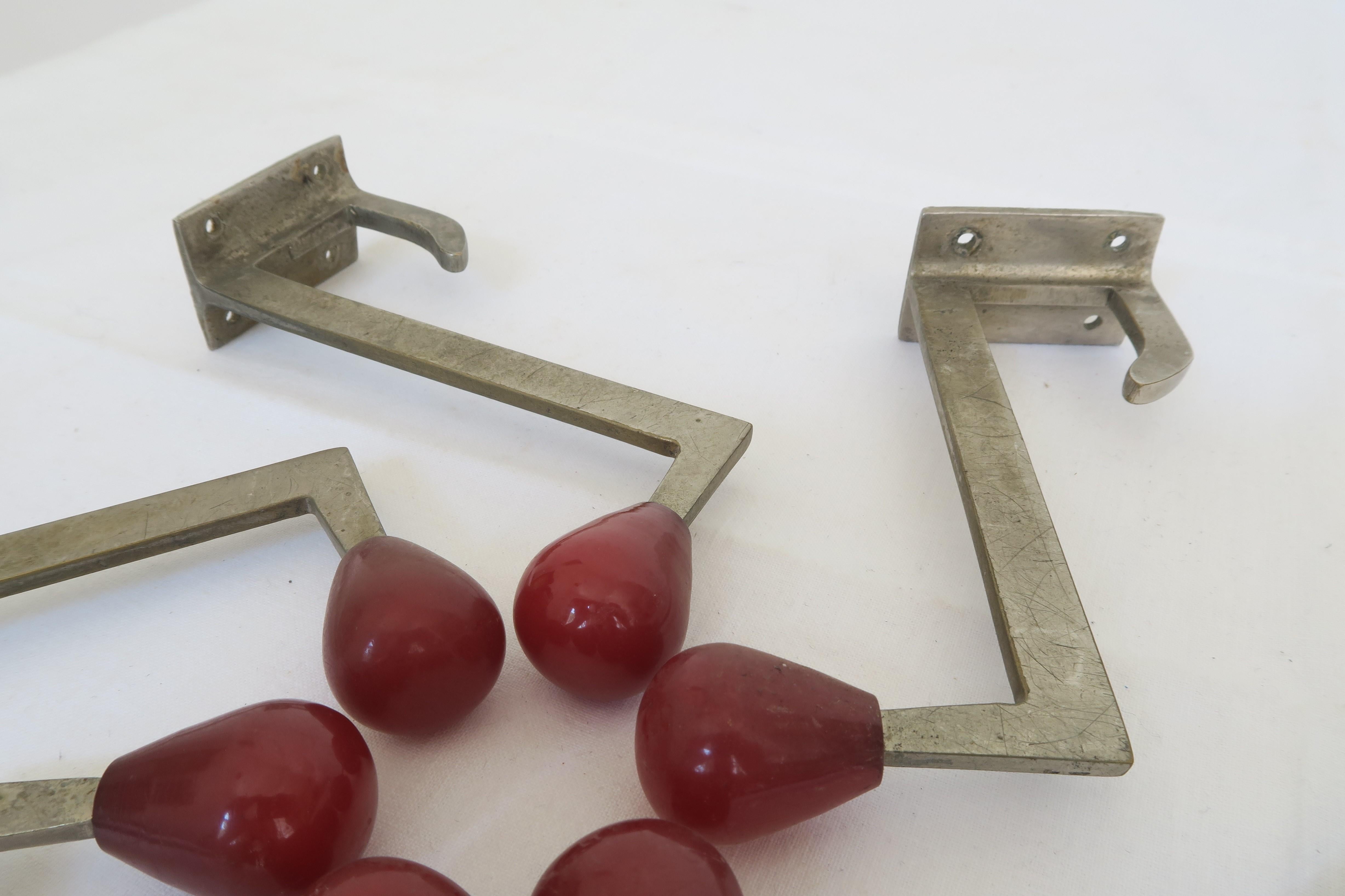 For sale is a exceptional set of six coat hooks. They were manufactured in the 1920s in the style of Art Deco. The hooks are made of solid brass and embellished with a deep red plastic cap at the tip. They can be mounted to the wall by use of four