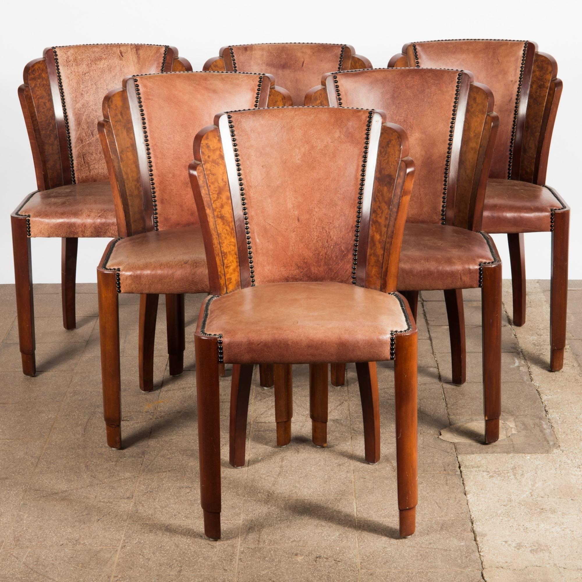A set of six Art Deco chairs. Structure of Thuja burl wood, back and padded seat with cognac leather cover and brass tacks.