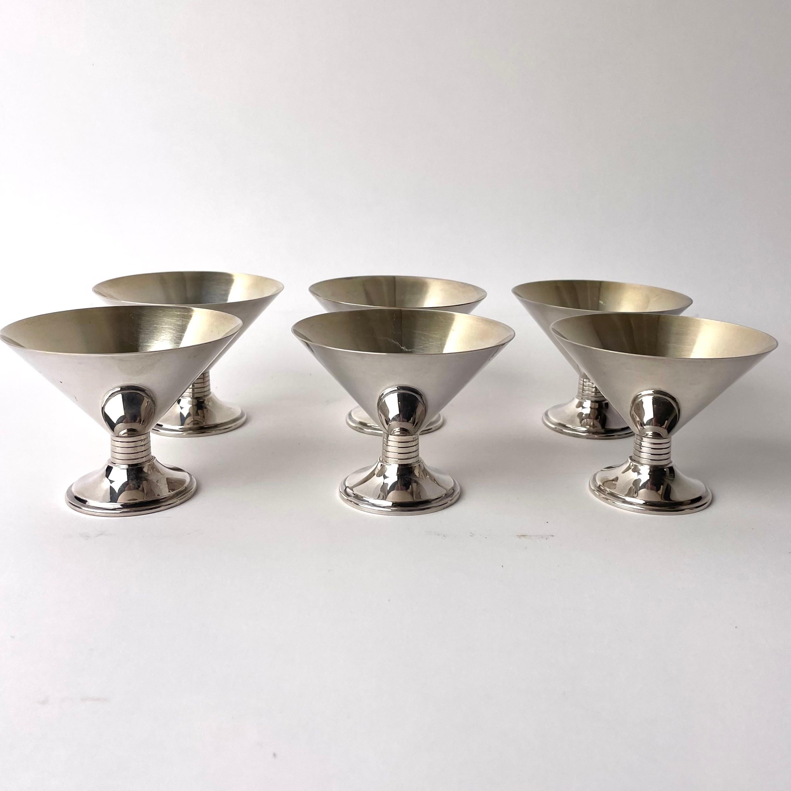 A set of six Art Deco cocktail glasses, produced during the 1920s or possibly the 1930s. The glasses are emblematic of Art Deco sensibility, combing a reverence for form and elegance, and rendering these ideas in modern material, here in silver