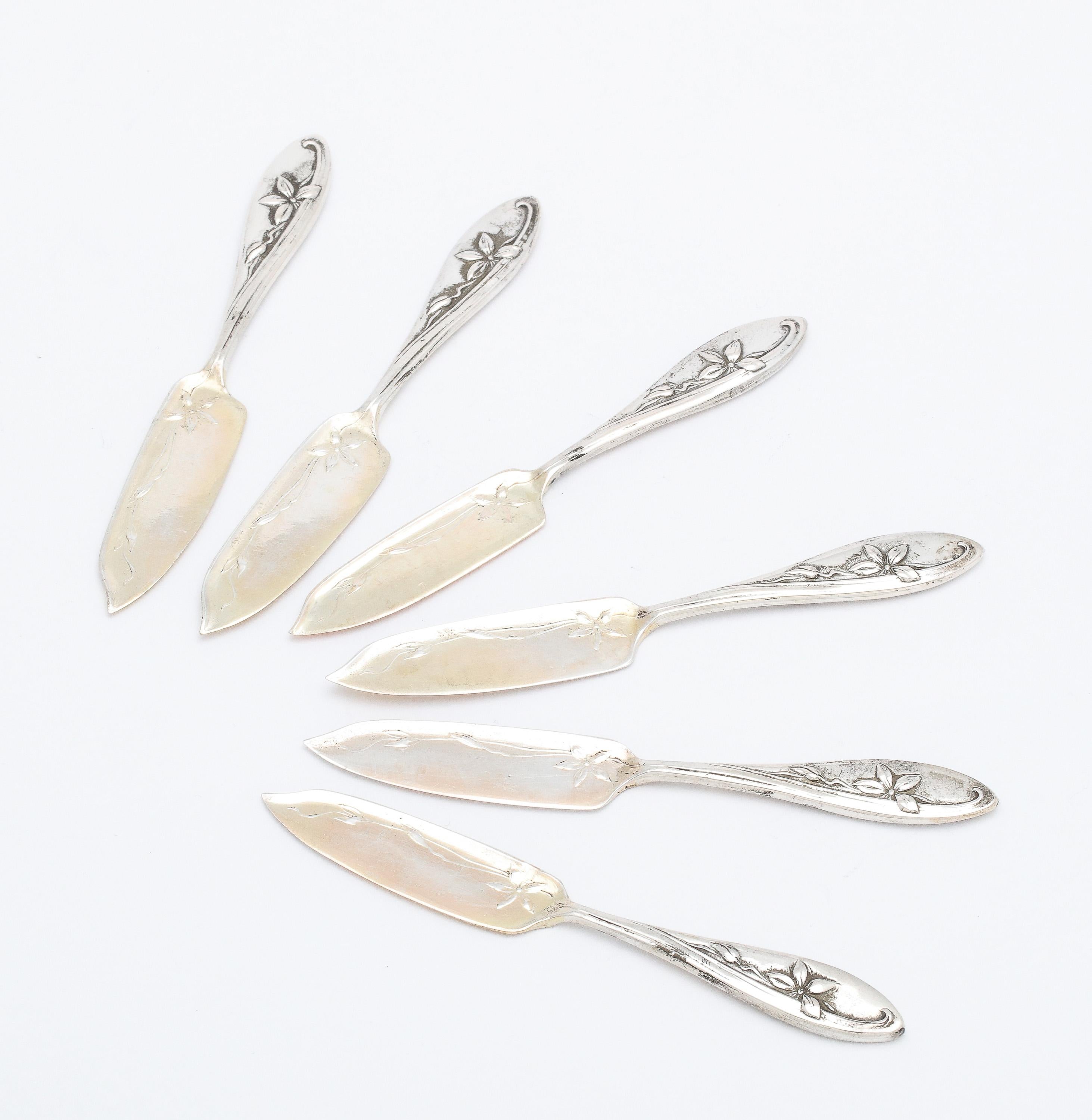 Set of  six, Art Nouveau, Continental Silver (.800) caviar/hors d' oeuvres spreaders, Germany, Ca. 1895-1910. Both sides of spreading surface are rose-gold gilded. Decorated with Art Nouveau lilies whose stems whip around the front and back of each
