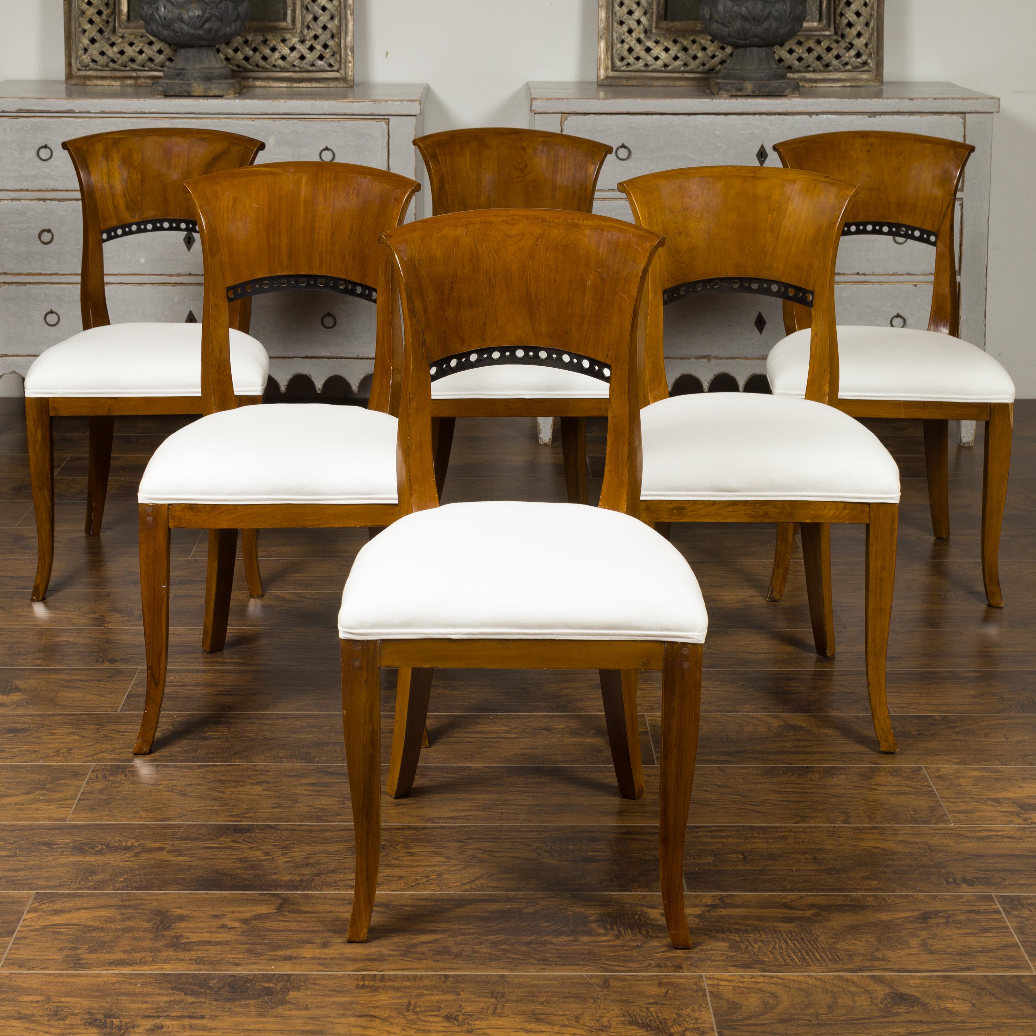 A set of six Austrian Biedermeier style walnut dining room chairs from the late 19th century, with ebonized accents and new upholstery. Born in imperial Austria during the last quarter of the 19th century, each of this set of six dining room side