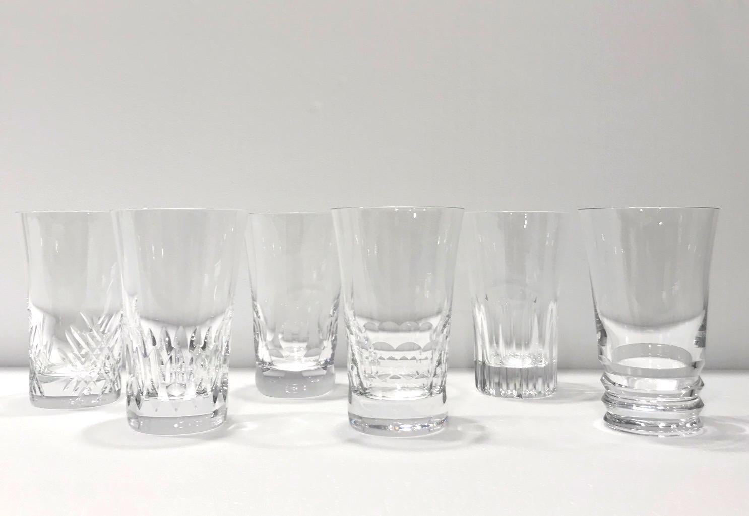 Set of six handcrafted crystal highball glasses each bearing a unique design. Blown crystal glasses feature exquisite handcut designs with geometric patterns, fluted accents, or crosshatched designs. Signed Baccarat on the underside of each glass.
