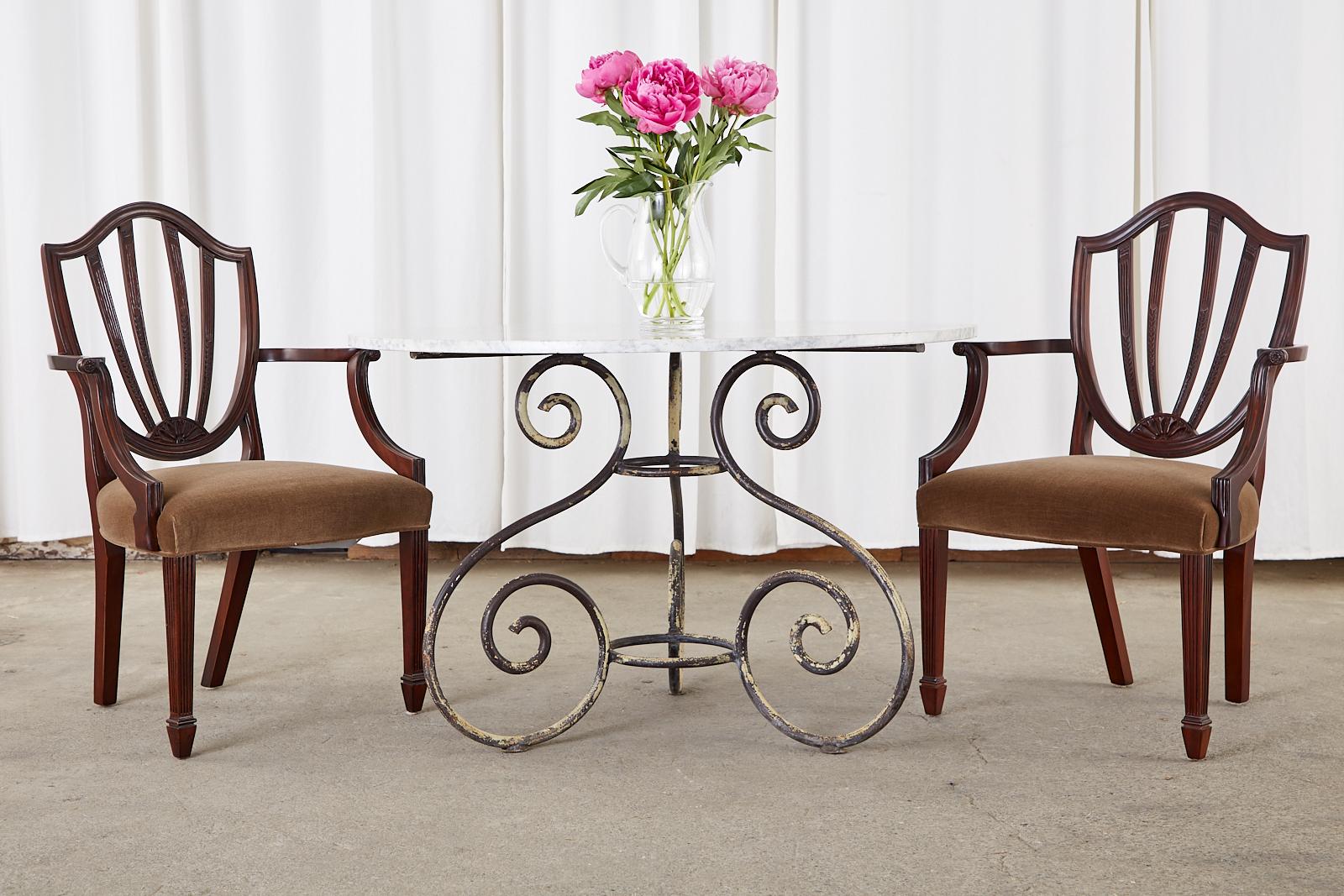 Distinctive set of mahogany dining chairs made by Baker from the historic Charleston collection. The chairs feature on Hepplewhite style shield back frame conjoined to gracefully curved serpentine arms. The set consists of two armchairs and four