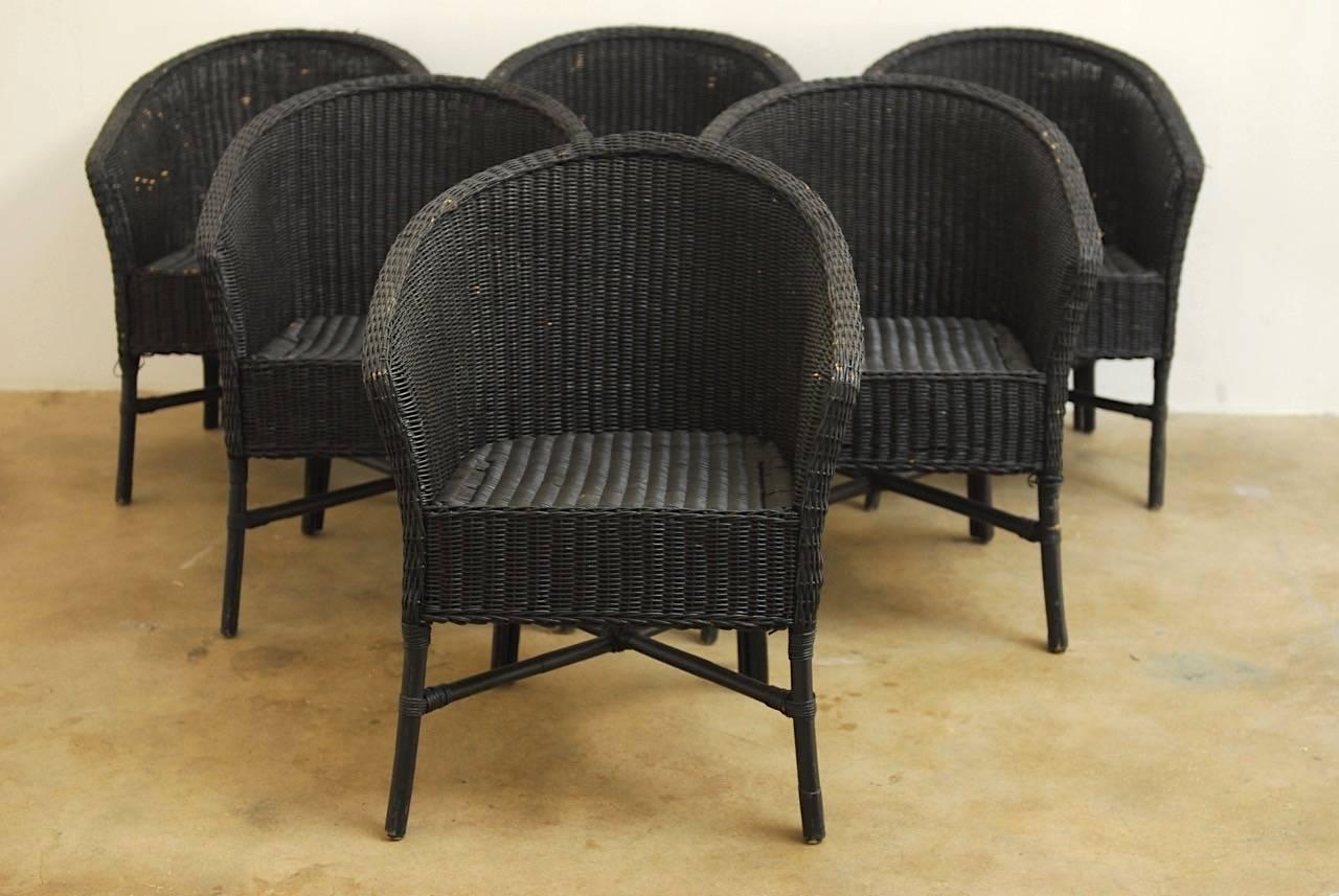Vintage set of six bamboo and wicker chairs made in a midcentury barrel back style. These chairs feature a black painted finish over the wicker. Supported by round rattan legs with X-form stretchers. Great for patio or garden use.