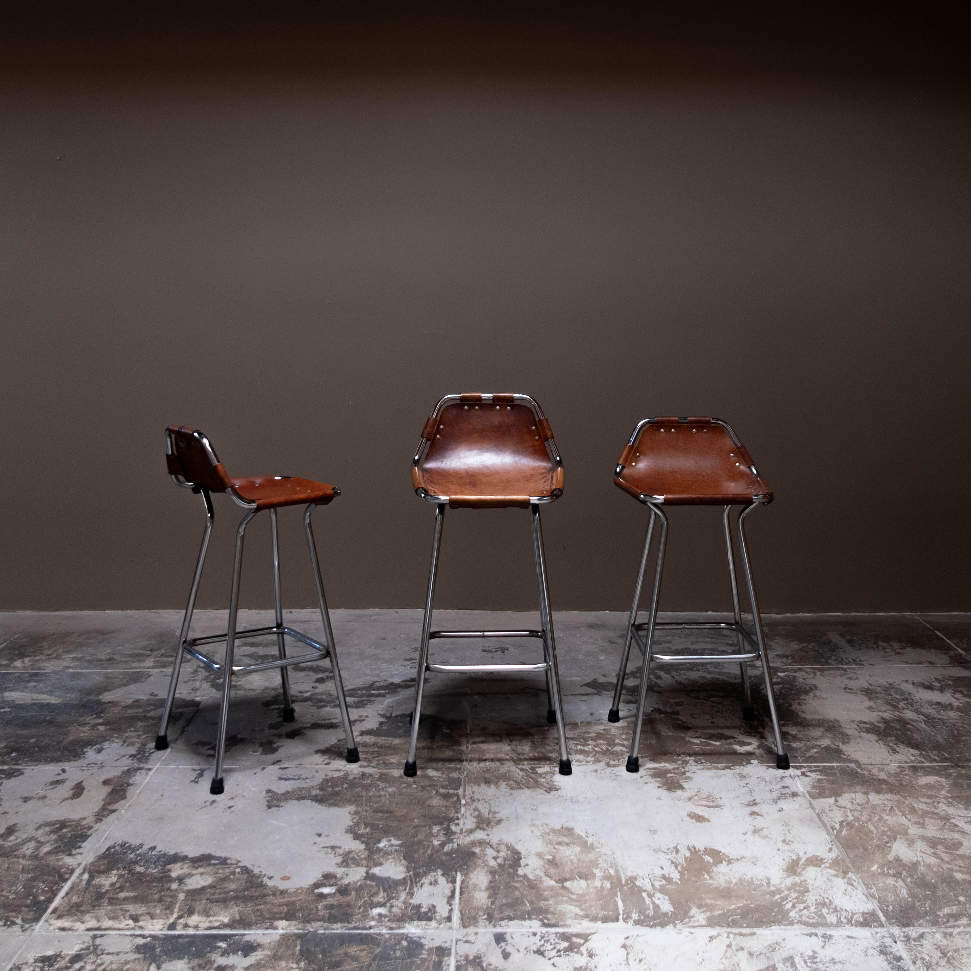 Magnifique ensemble de tabourets de bar conçus par Charlotte Perriand pour la station de ski des Arcs, France 1960. Ces tabourets emblématiques présentent une combinaison de charme rustique et de force industrielle. Les sièges sont fabriqués à la