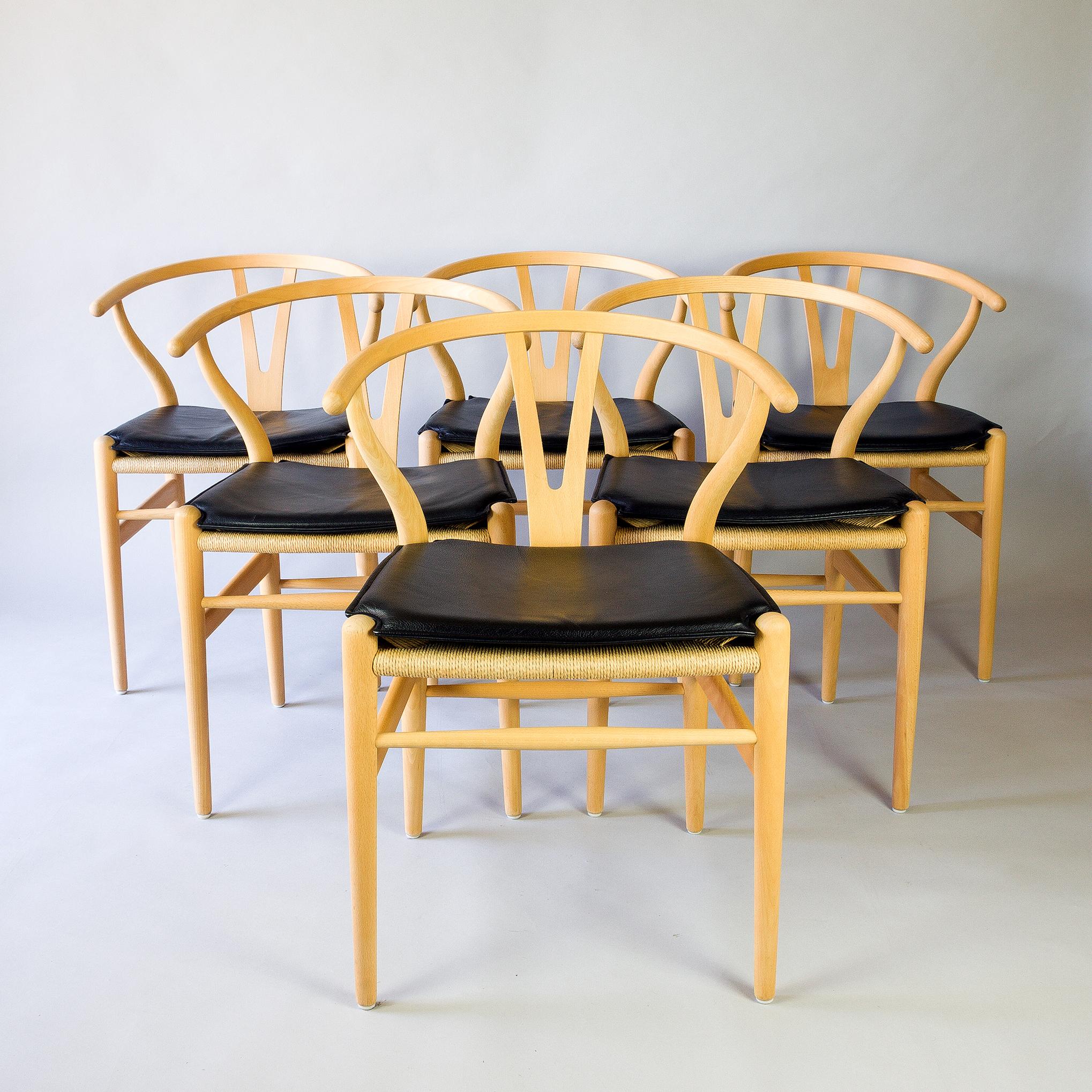 Hans Wegner CH24 Wishbone chairs in beech with black leather cushions, approximately 5 years old these chairs are in excellent condition. The paper cord seats are very tight and we have thoroughly cleaned the chairs and have treated them with