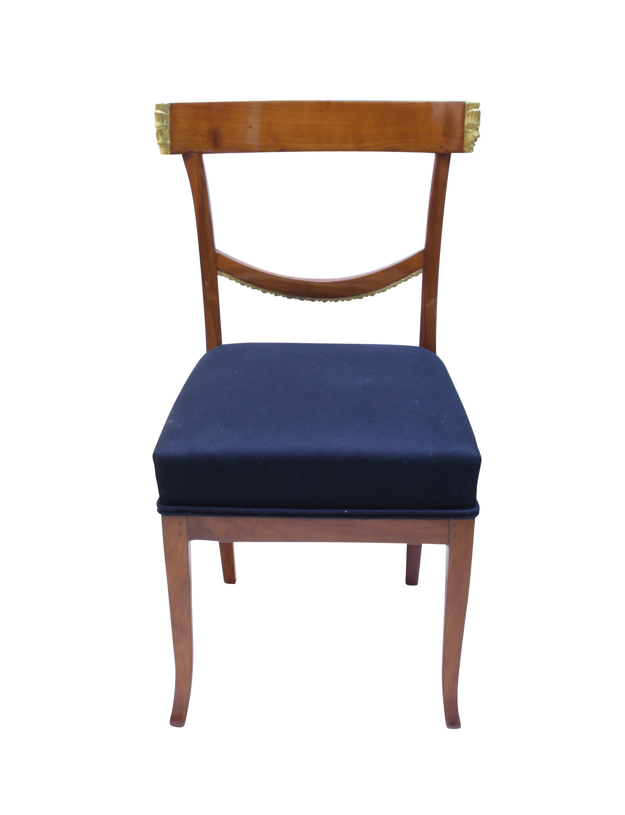 Wonderful Set of Six Biedermeier Dining Room Chairs from South Germany around 1820. 

Very special are the curved-out (not put on) faces at the side of the backrests. On the front, these have profiles of faces that have been plated with gold. From