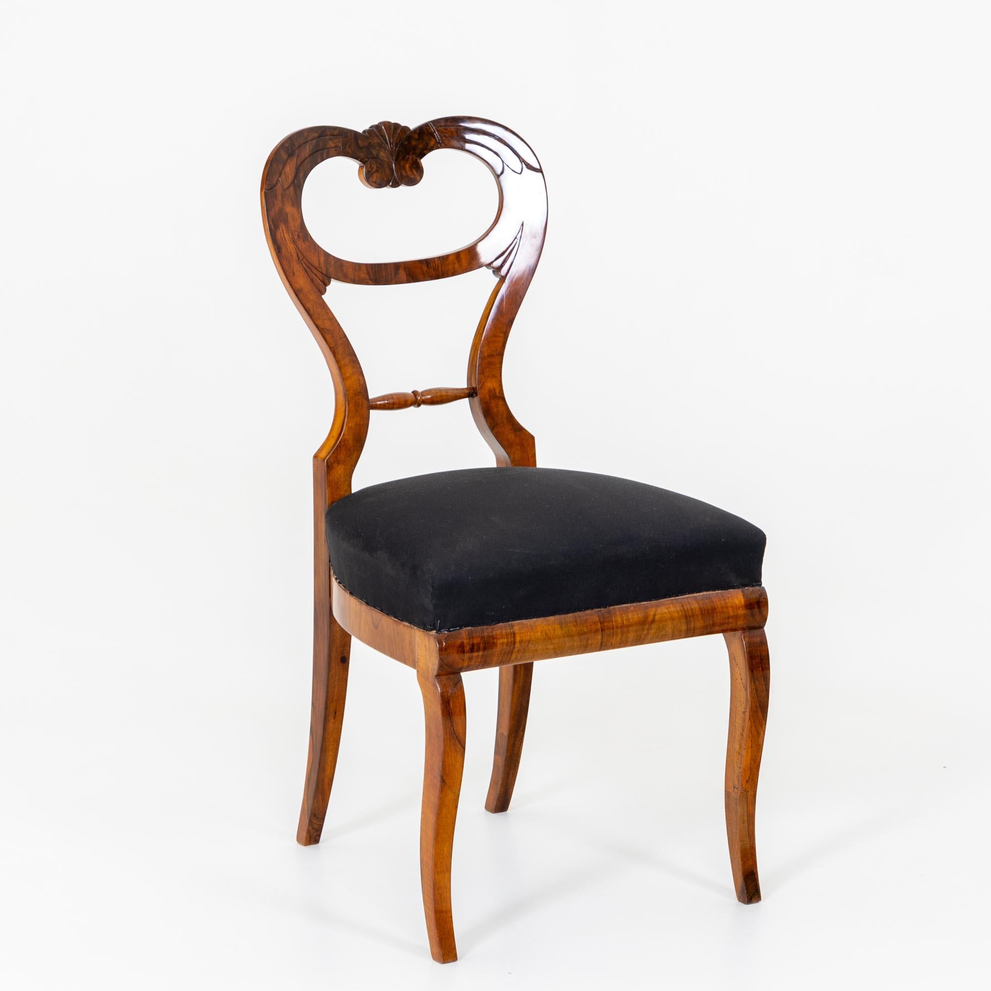 Set of six Biedermeier dining chairs in walnut, solid and veneered. The chairs stand on elegantly curved legs and have heart-shaped backs with fan decoration. The chairs have been reupholstered and covered with a black ground fabric and polished by