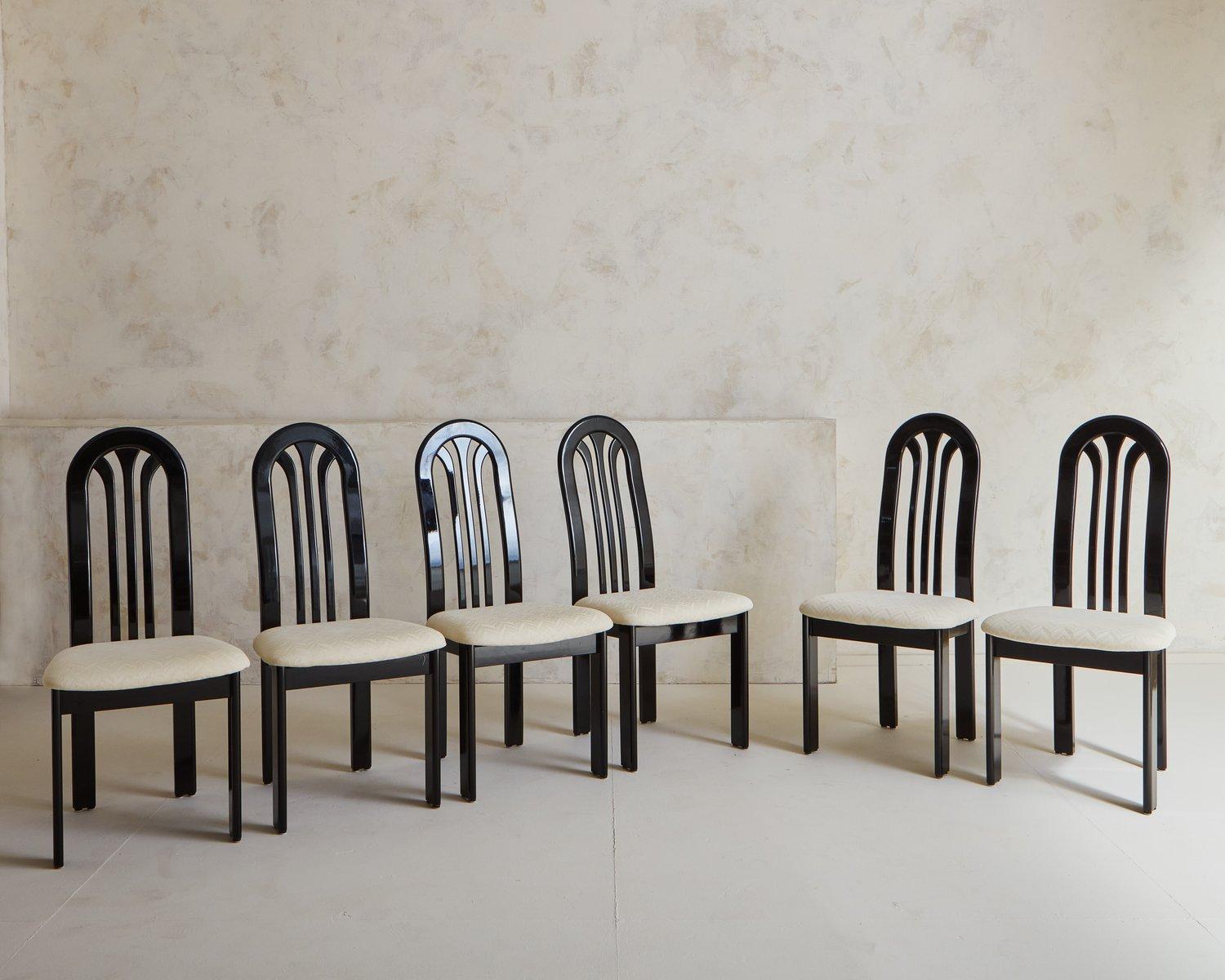 A set of 6 Postmodern 1980s black lacquered dining chairs by German manufacturer Lübke for Roche Bobois. These chairs feature curved backs and upholstered seats in original cream herringbone fabric.