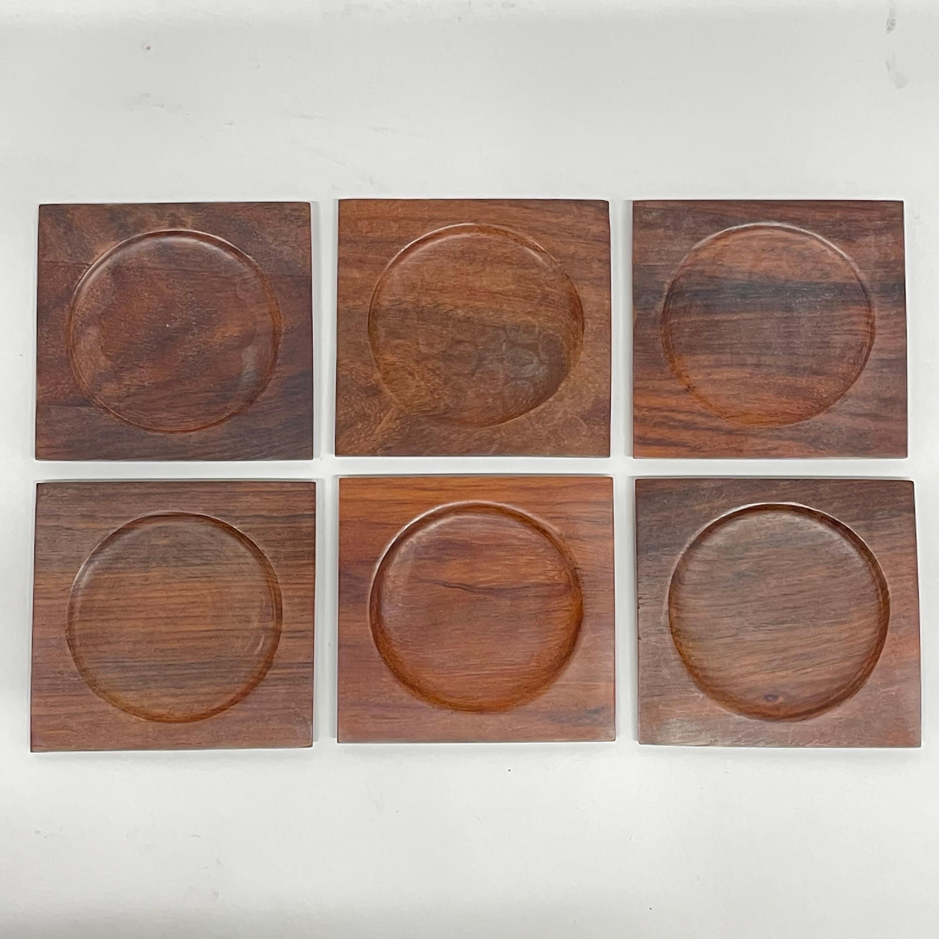 Set of Six organic Mid-Century Modern coasters rendered in hand carved Brazilian rosewood in a square shape with a inset circular indention for cups and glasses to set, Brazil, Circa 1960s.