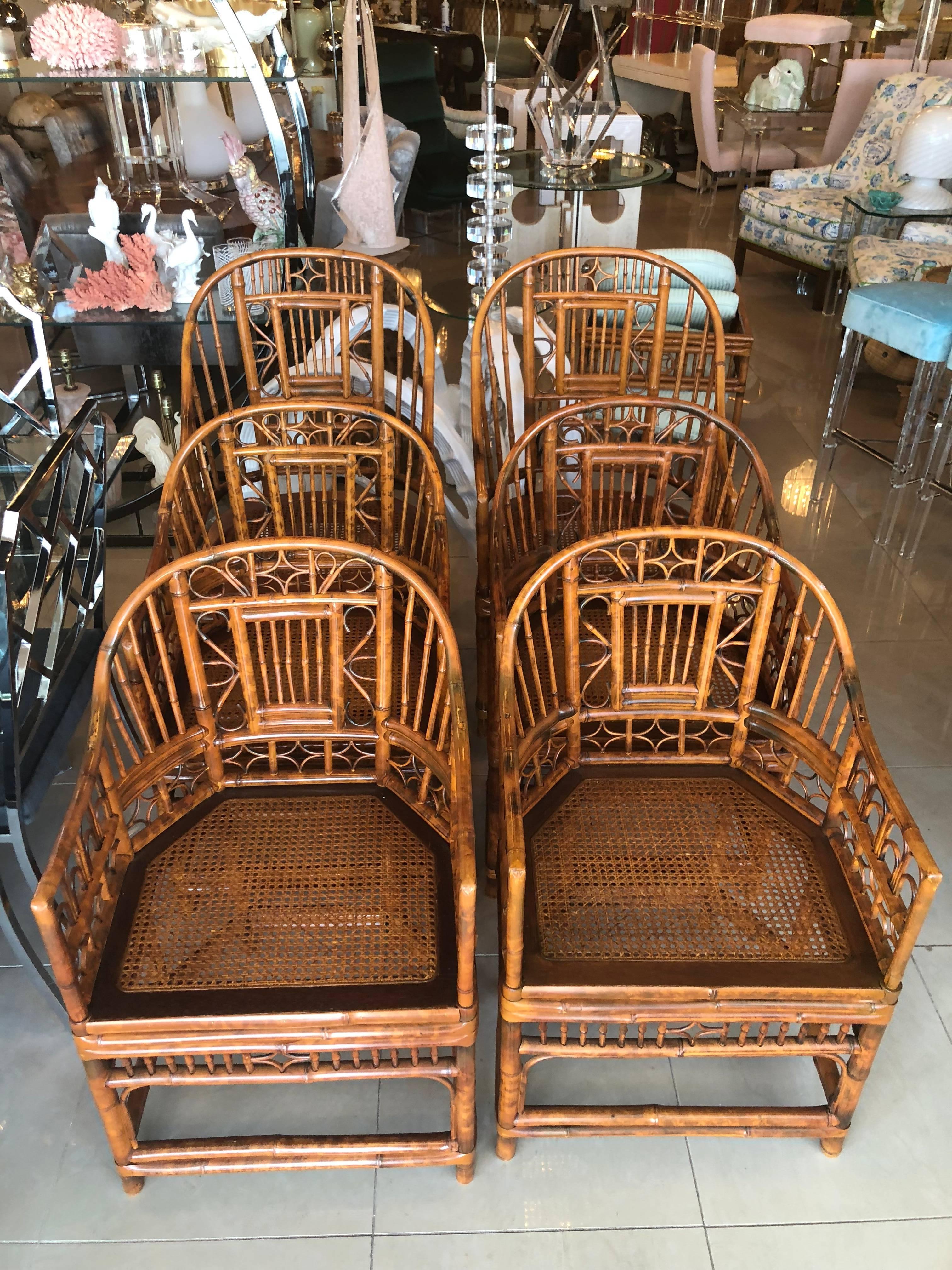 Vintage set of six Brighton style bamboo arm dining chairs. Burnt bamboo tortoise shell finish. Includes two larger captains chairs. Cane seats. These are in excellent condition. 
Two larger chairs measure 40.5 tall x 21.5 wide x 17.25 seat height