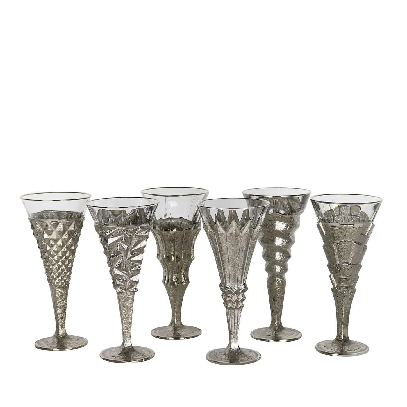This set of six flutes is part of the Capriccio collection and comprises assorted pieces that are each a one-of-a-kind objects of functional design. They were carved from solid glass into six striking shapes that create abstract decorations on the