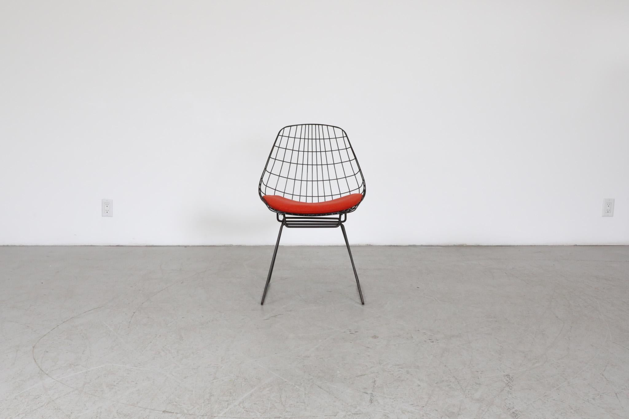 Ensemble de six chaises en fil de fer 'SM05' de Cees Braakman pour Pastoe, années 1950. D'un style minimaliste classique, ces chaises à structure métallique émaillée noire sont élégantes et sophistiquées et sont dotées de coussins d'assise rouges