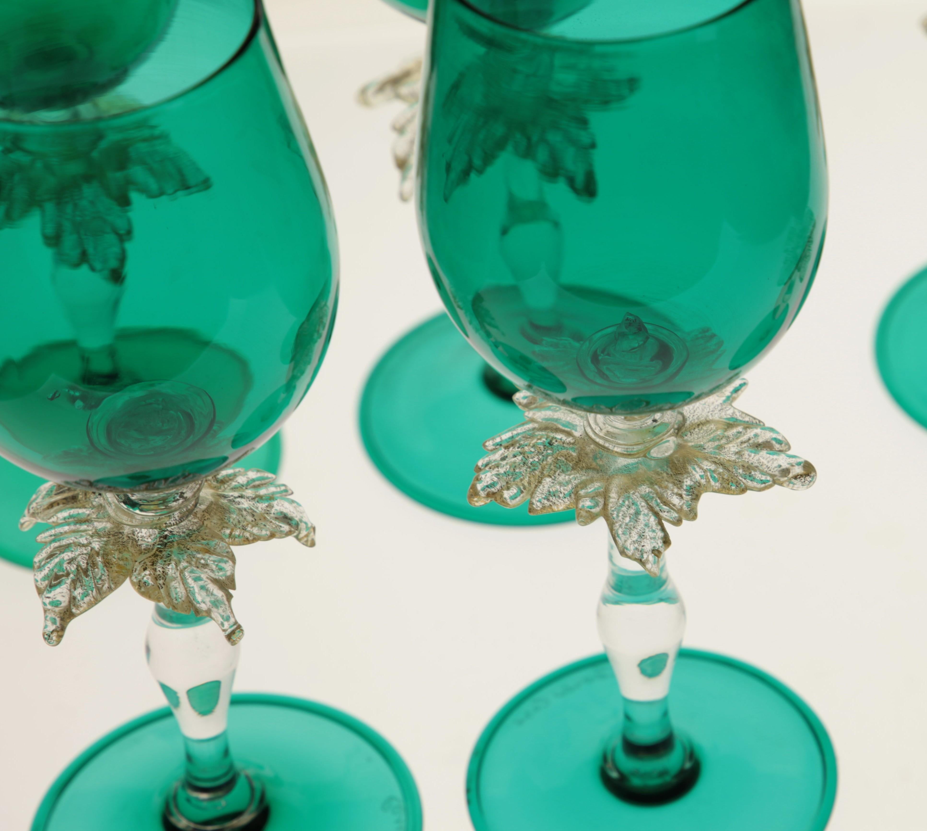 Set of six stemmed glass from Cenedese, made in Murano.
 
The glasses are in green with a palm leaf design in-between the stem and the glass. The leaf contains elements of gold leaf that glimmers when light reflects on it.
 
Celebration present and