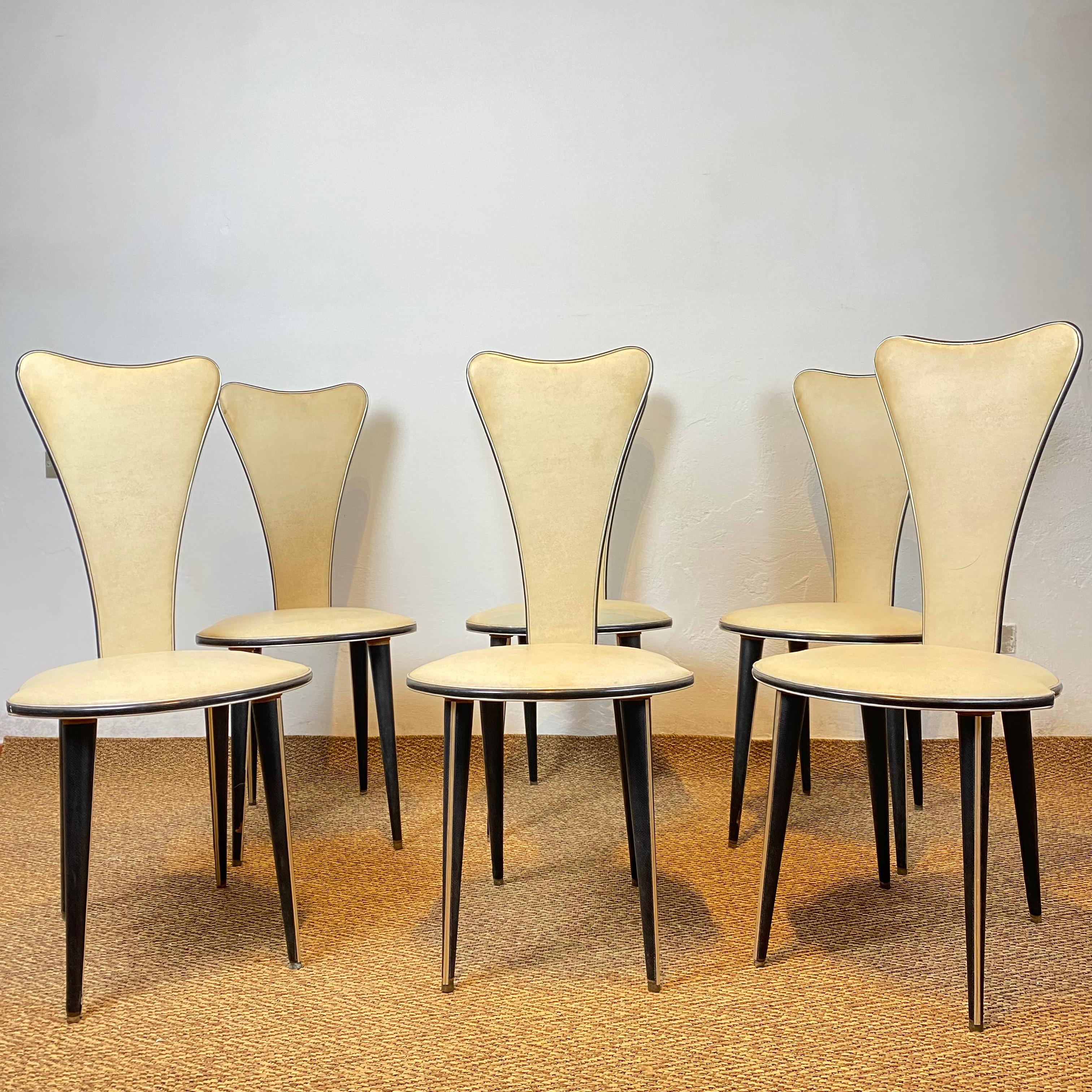 Six dining chairs designed by Umberto Mascagni of Bologna in the 1950s. The main body frame is solid European wood, covered in cream-colored grained vinyl and anodized aluminum. The legs are also covered in black vinyl. Slight signs of aging as