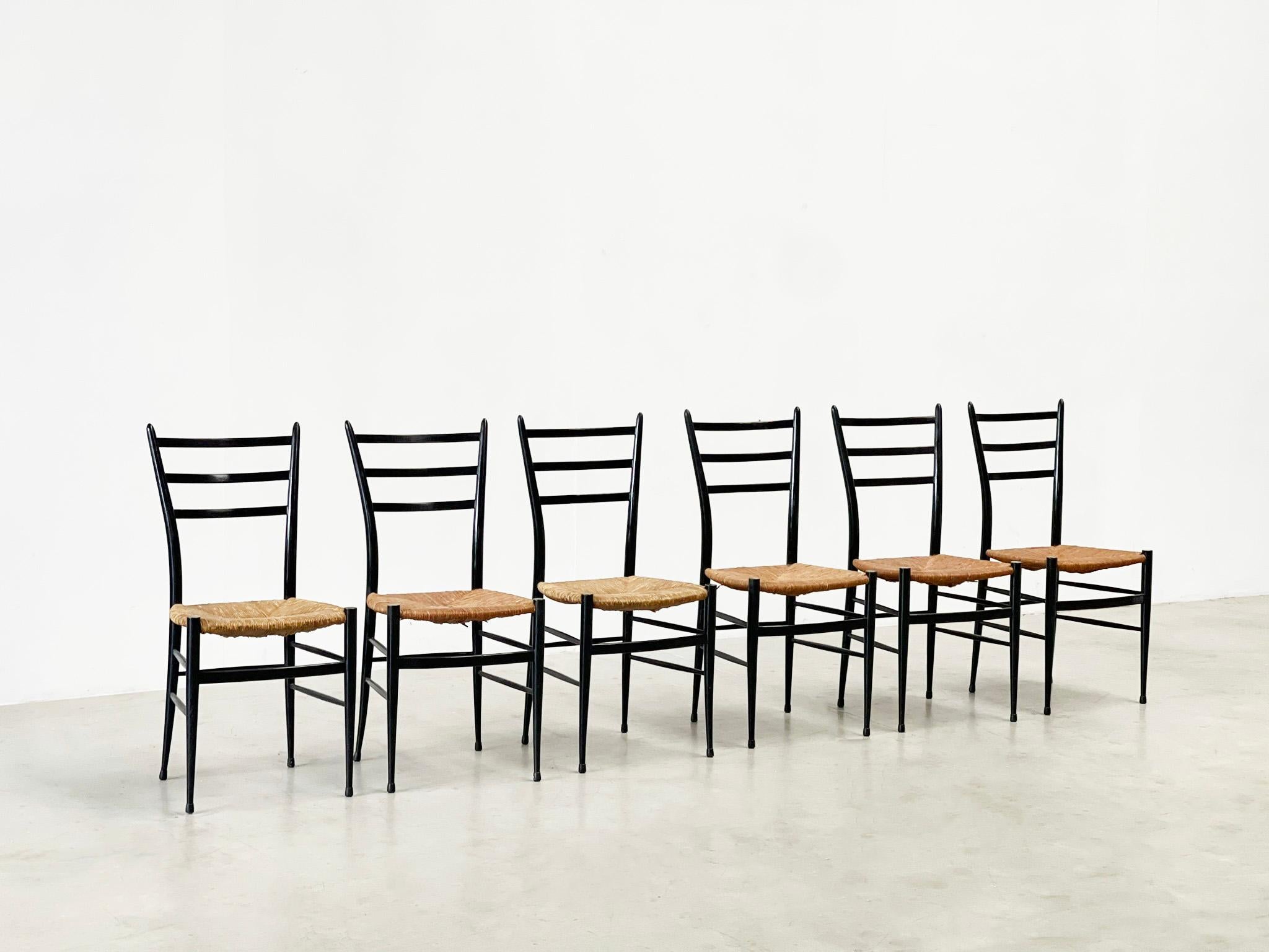 Beautiful set of 7 chiavari chairs with a black ebonize frame and a rattan seat. The chairs were designed by Giuseppe Gaetano Descalzi and produced since the early 1970's in the Ligurian town of Chiavari, Italy.

 

It is said that this chairs