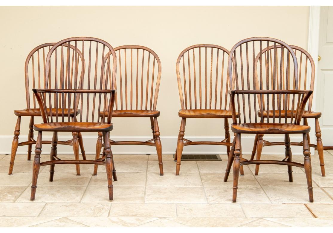 A beautifully finished set of traditional bow back Windsor chairs with excellent graining and comfort. Including two armchairs and two side chairs in a honey tone stained oak. The hoop backs attach to the shaped seats that are raised on turned