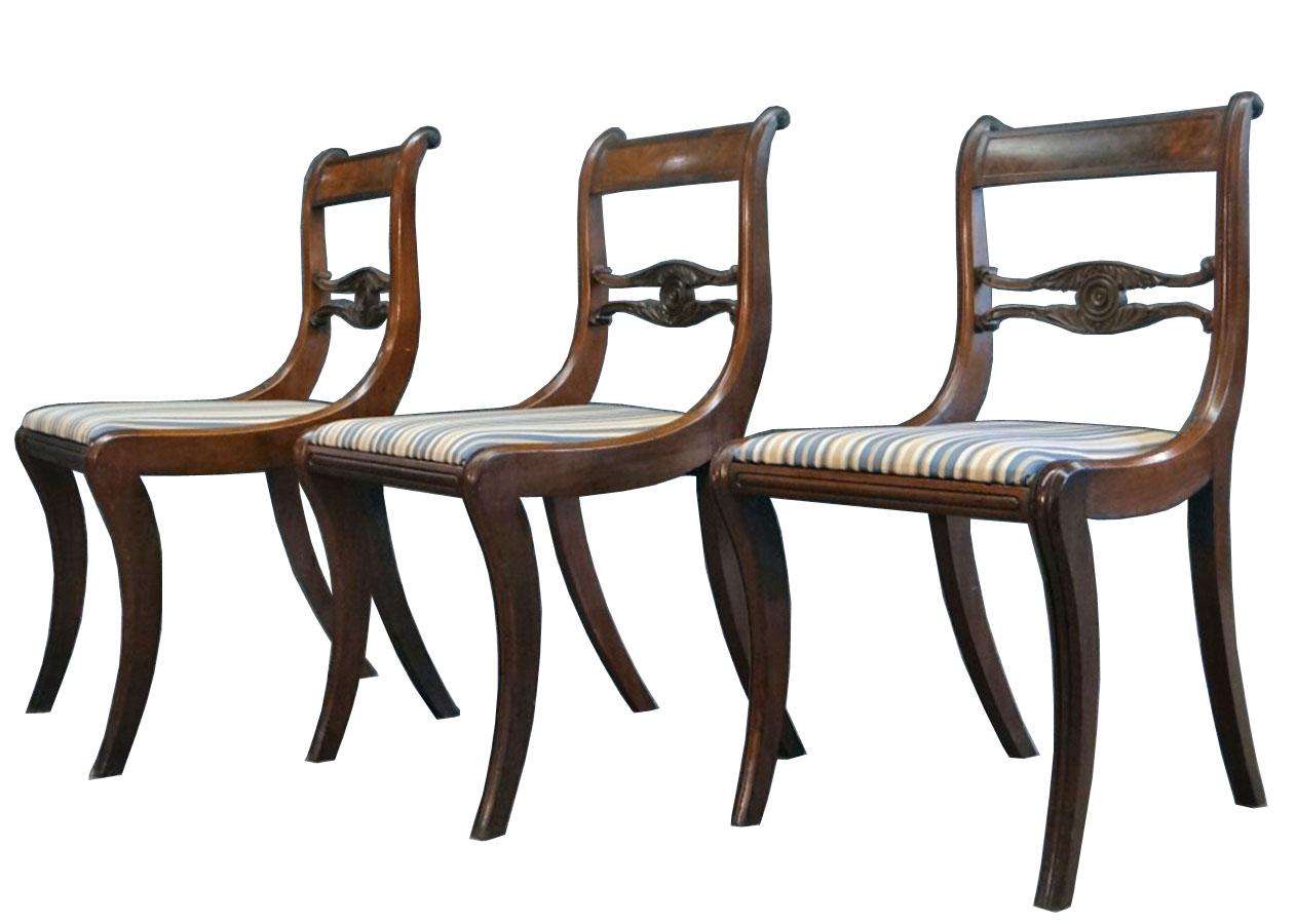 A very fine set of six federal-era saber leg dining chairs, attributable to New York cabinetmaker, Duncan Phyfe. Made of a fine and dense mahogany, these American classical chairs offer a figured mahogany veneer on the crest rail, a carved centre