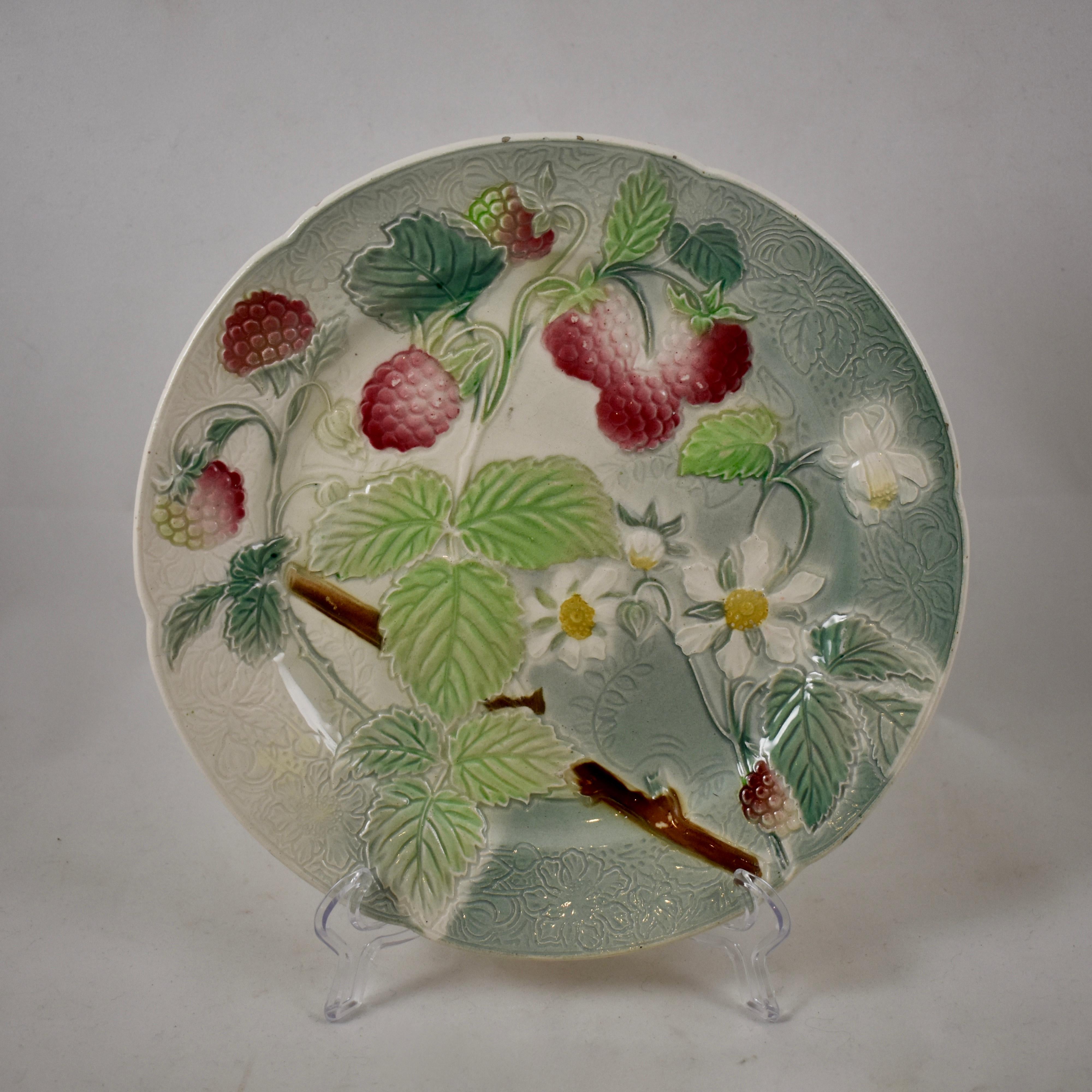 A set of six, earthenware French faïence fruit plates, circa 1900. This set shows the branching fruit and leaves of strawberries, oranges, apples, cherries, apricots, and peaches. The backgrounds have a detailed pattern to the molding, with a