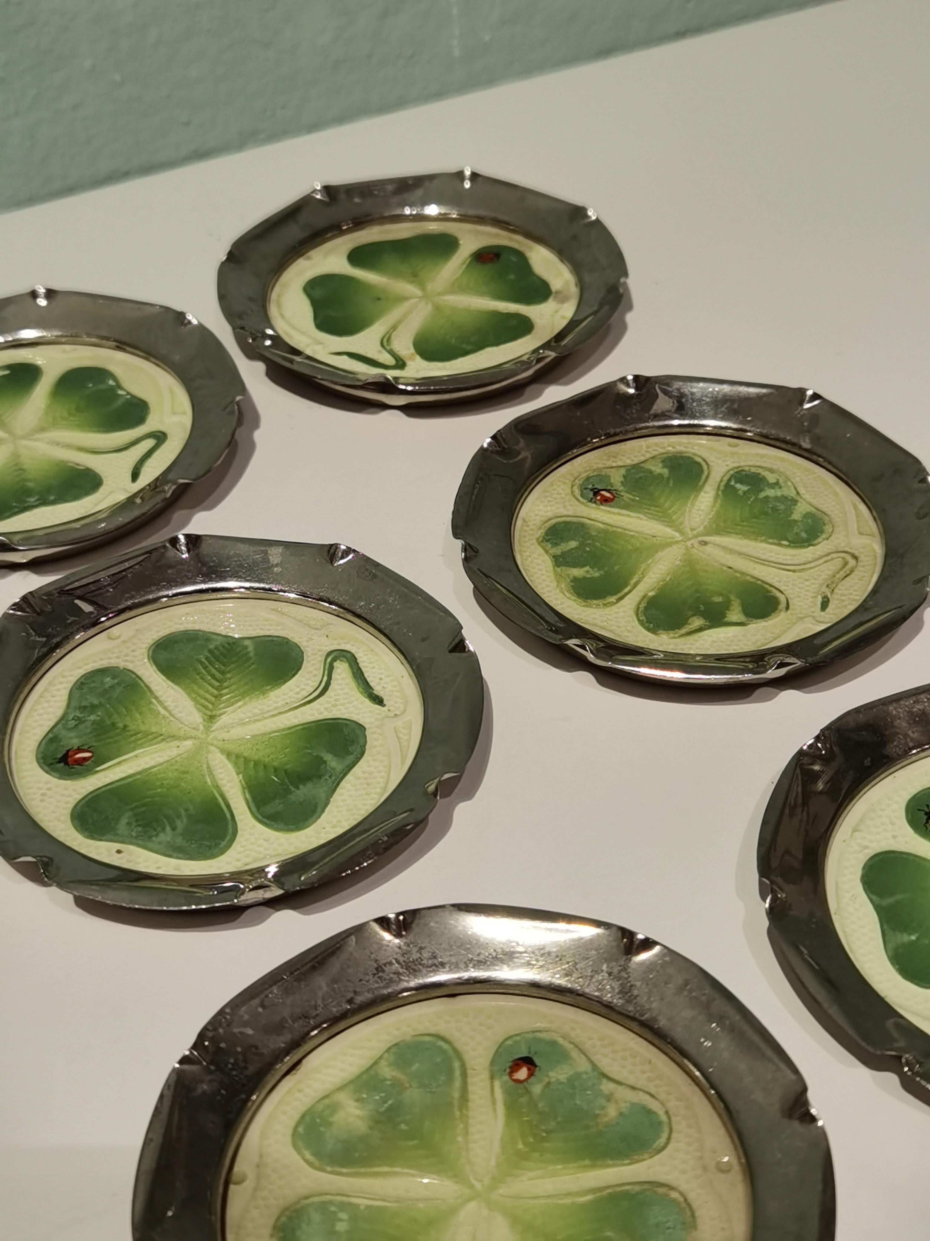 Set of six coasters with enameled four-leaf clover in green on cream white pottery.
Metal framed in the style of Art Nouveau. Backside pattern numbers and initials. Made in Germany.