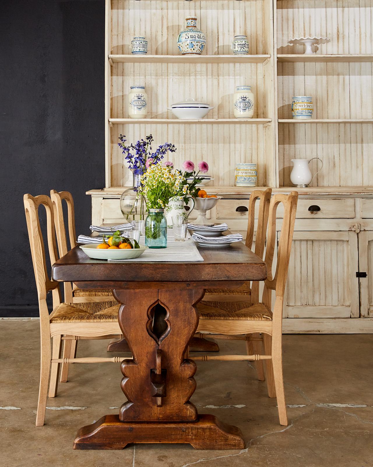 Rustic set of six oak dining chairs with rush seats made in the country French provincial taste. The chairs feature a bleached oak finish with a natural patina that showcases the lovely woodgrain patterns of the oak. The carved frames have