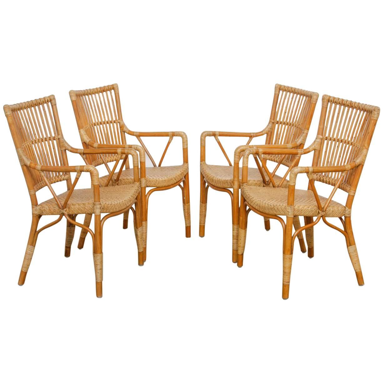Stylish set of Six Danish modern dining chairs constructed from bamboo, rattan, and wicker. These Scandinavian chairs are made in the manner of McGuire with bent rattan frames. Square back rests are joined to a soft woven seat supported by round