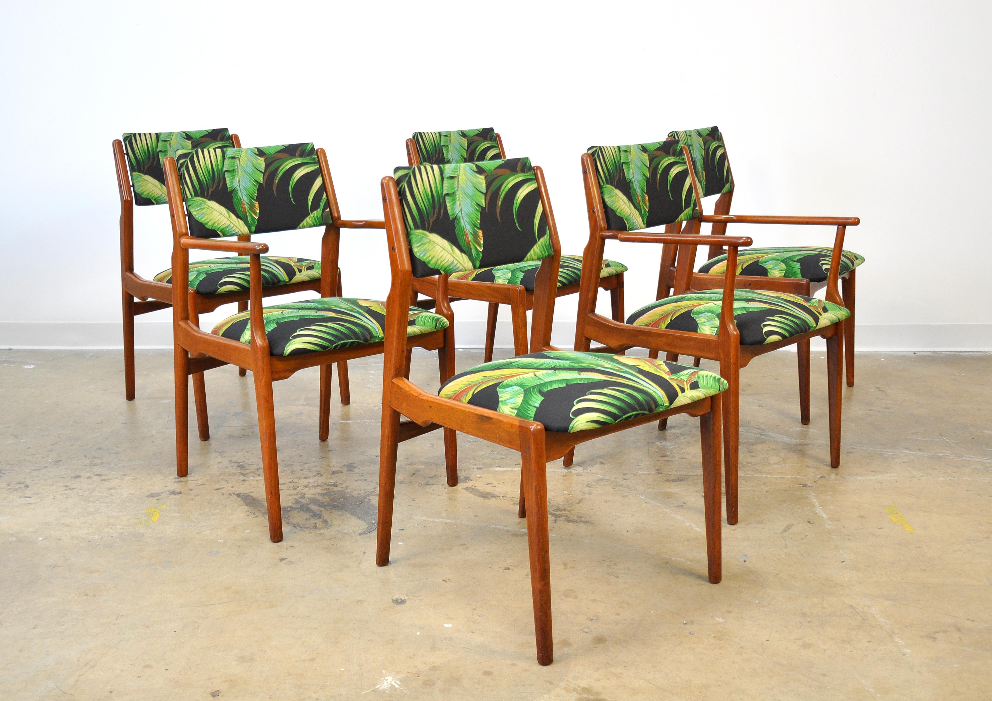 Set of six vintage midcentury dining chairs including four side chairs and a pair of armchairs or captain's chairs, dating from the 1960s. The sculpted solid teak frames feature upholstered floating backrests with brass connectors. The seats and