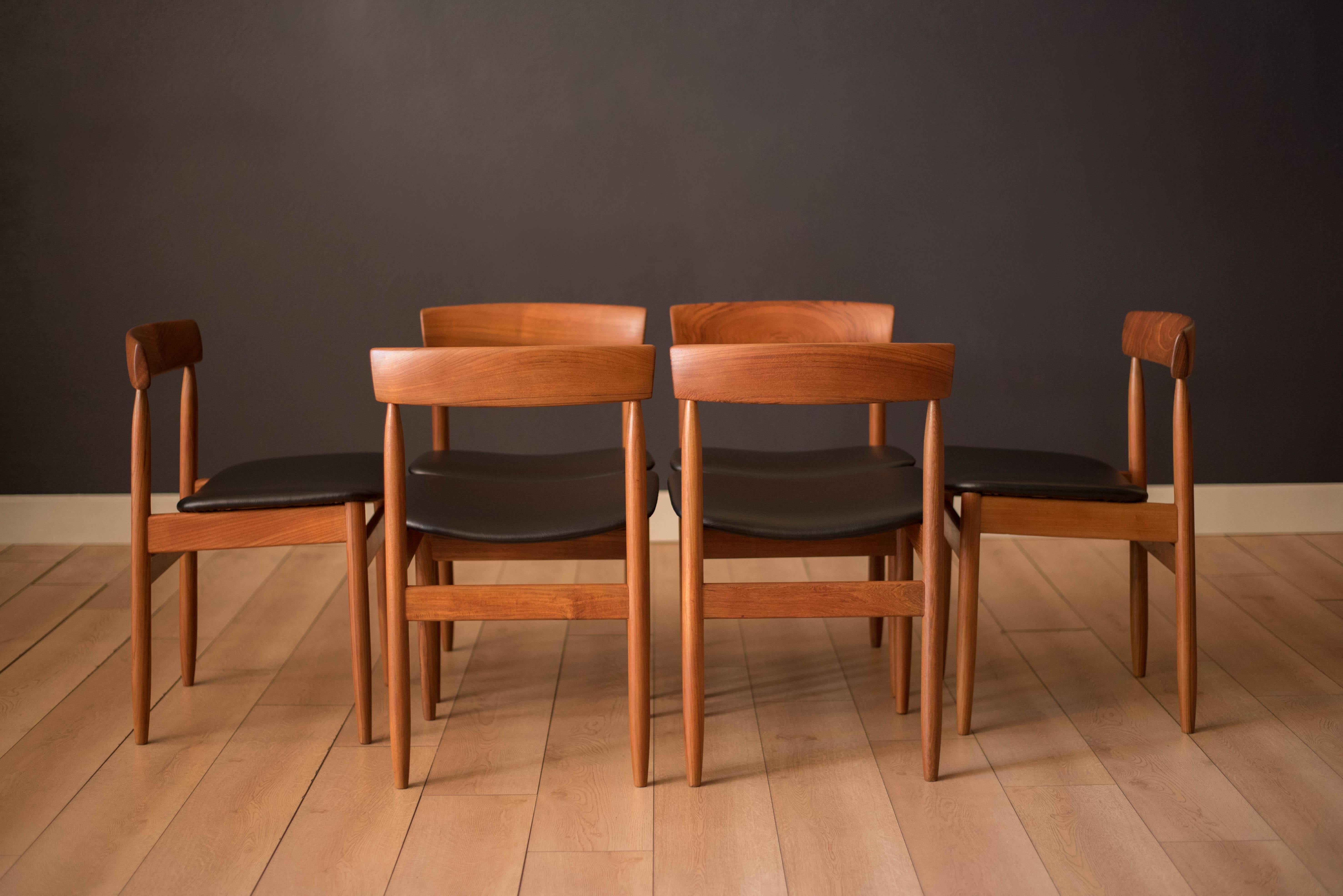 Mid century modern dining chairs in teak designed by Arne Hovmand-Olsen for Mogens Kold, Denmark. Each individual chair is crafted with a curved solid paddle backrest and sculptural supporting legs. This set has been newly reupholstered in black