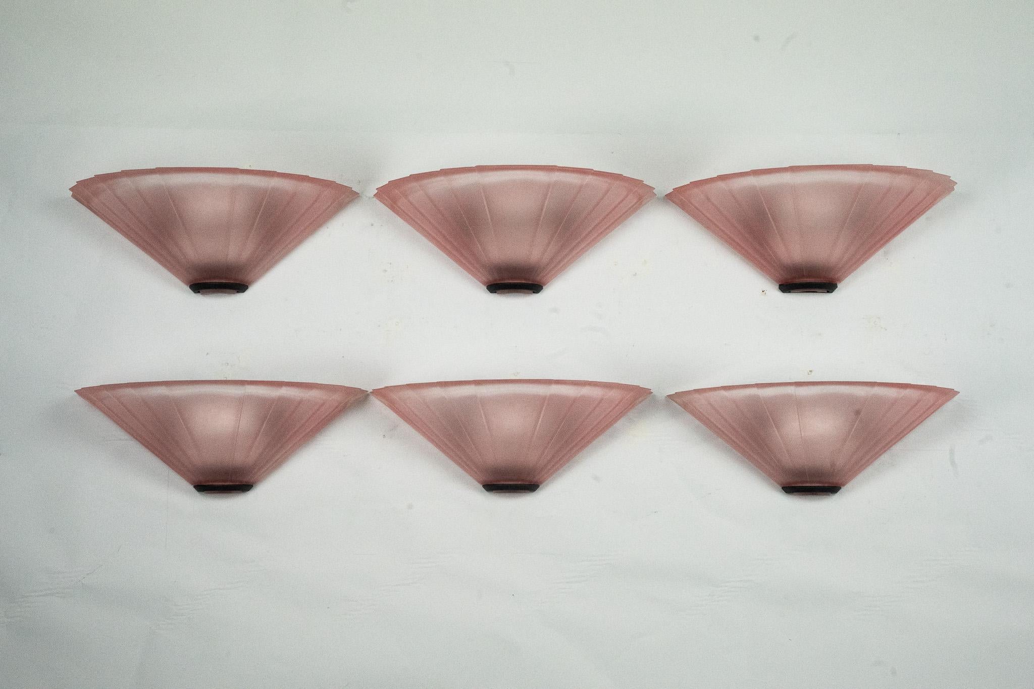Elegante conjunto de seis apliques de pared fabricados por De Majo en la década de 1980. Cada pieza presenta un diseño en forma de abanico en cristal de Murano rosa texturizado, que evoca inspiraciones Art Déco al tiempo que refleja la refinada