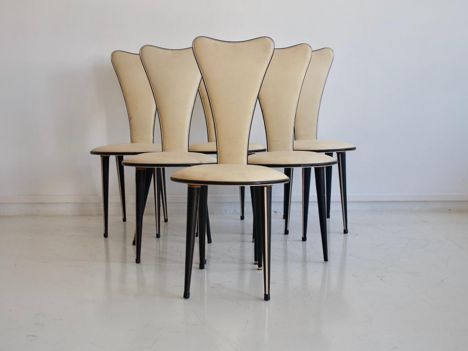 Set of six chairs from the 1950s, Italian design by Umberto Mascagni. Conical wooden legs covered with black vinyl and with inlaid gold metal trim. Seat and back covered in cream white vinyl with black edging. Traces of wear commensurate with age,