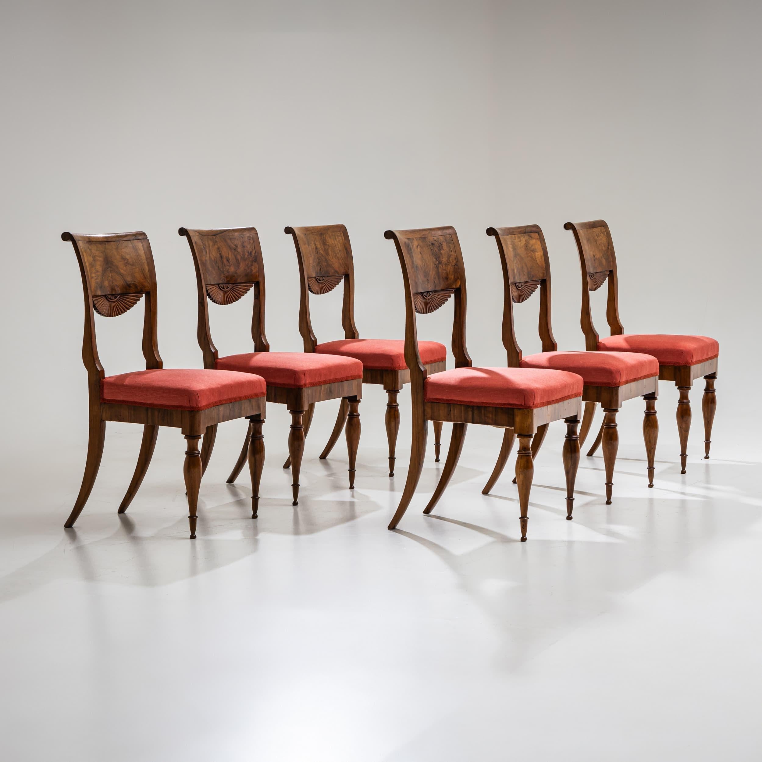 A set of six walnut dining chairs featuring front baluster legs and splayed saber legs at the back. The gently scrolled backrests terminate in an elegant velarium-style carving. The chairs remain in an unrestored condition, preserving their original